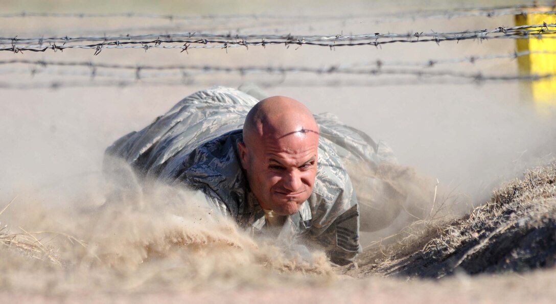 Master Sgt. Thomas Carpino, 28th Security Forces Squadron operations flight chief, low crawls under barbwire during the Global Strike Challenge competition at Camp Guernsey, Wyo., Sept. 25, 2014.  Carpino and his team competed in the three-day challenge testing their tactics, shooting, mental and physical capabilities. (U.S. Air Force photo by Tech. Sgt. Jerry Fleshman/Released)