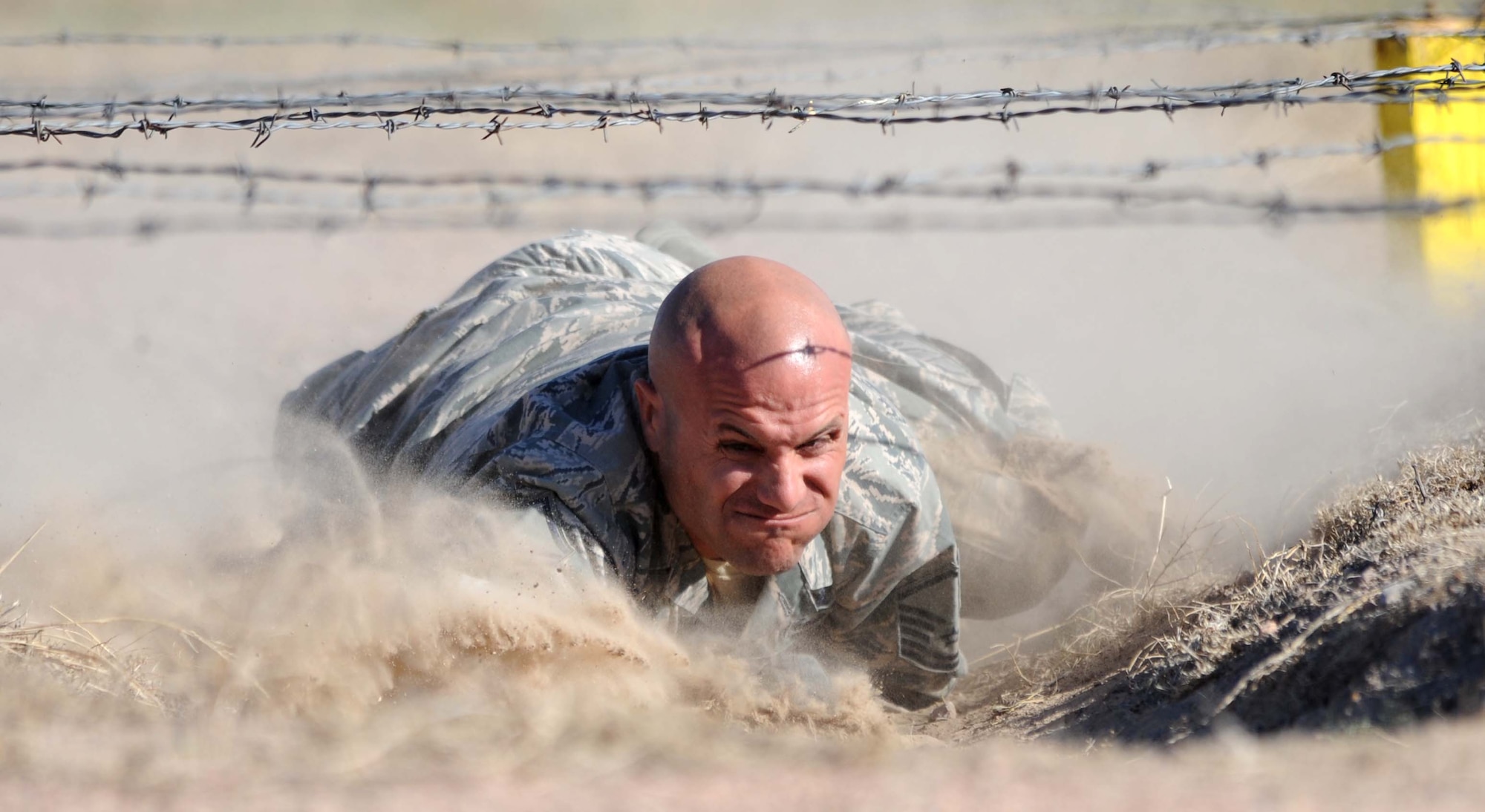 Master Sgt. Thomas Carpino, 28th Security Forces Squadron operations flight chief, low crawls under barbwire during the Global Strike Challenge competition at Camp Guernsey, Wyo., Sept. 25, 2014.  Carpino and his team competed in the three-day challenge testing their tactics, shooting, mental and physical capabilities. (U.S. Air Force photo by Tech. Sgt. Jerry Fleshman/Released)