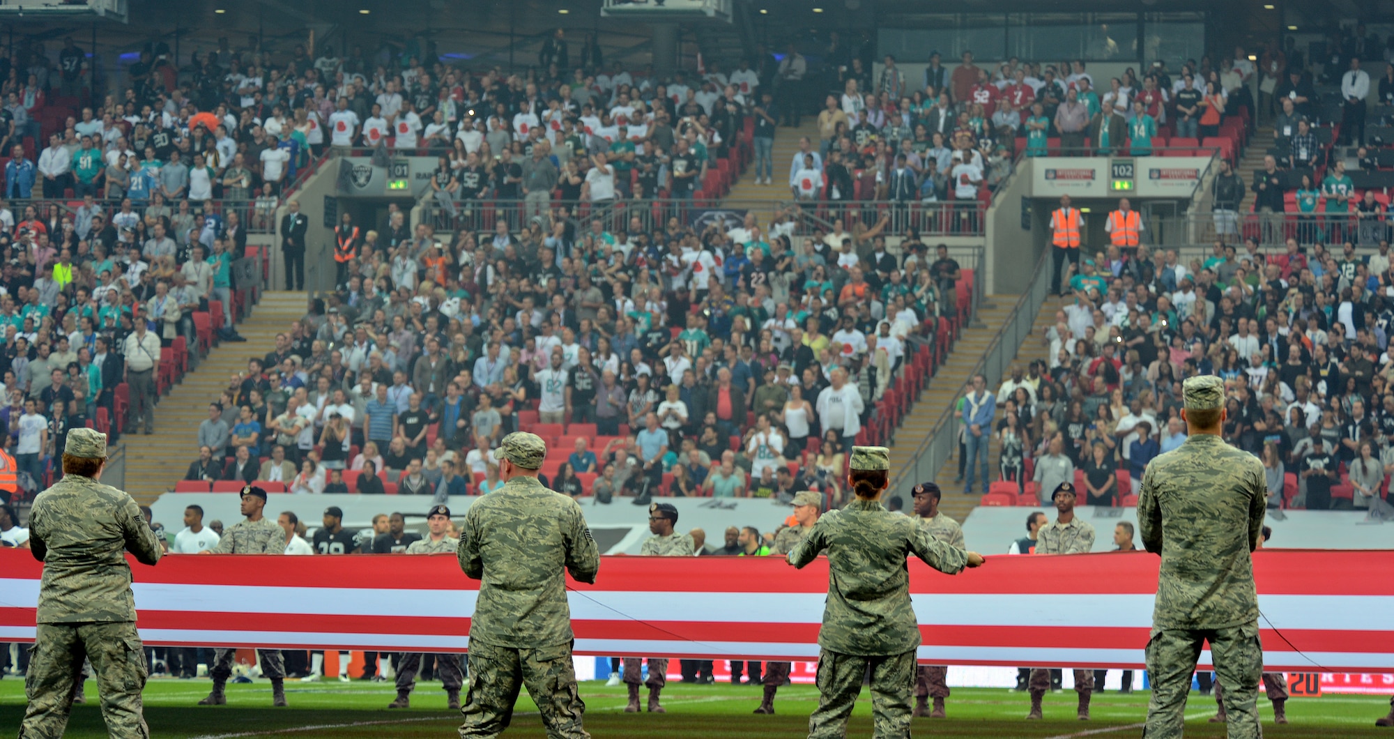 Airmen from Royal Air Force Lakenheath, England, hold the U.S. flag before the Miami Dolphins – Oakland Raiders football game in London on Sept. 28, 2014. The game was the first of three international NFL games that will be played this season at Wembley Stadium. As part of the pregame ceremony, the 48 Fighter Wing Airmen presented U.S. and U.K. flags as a sign of the continued cooperation between U.S. visiting forces and their U.K. hosts. (U.S. Air Force photo by Airman 1st Class Trevor T. McBride)  
