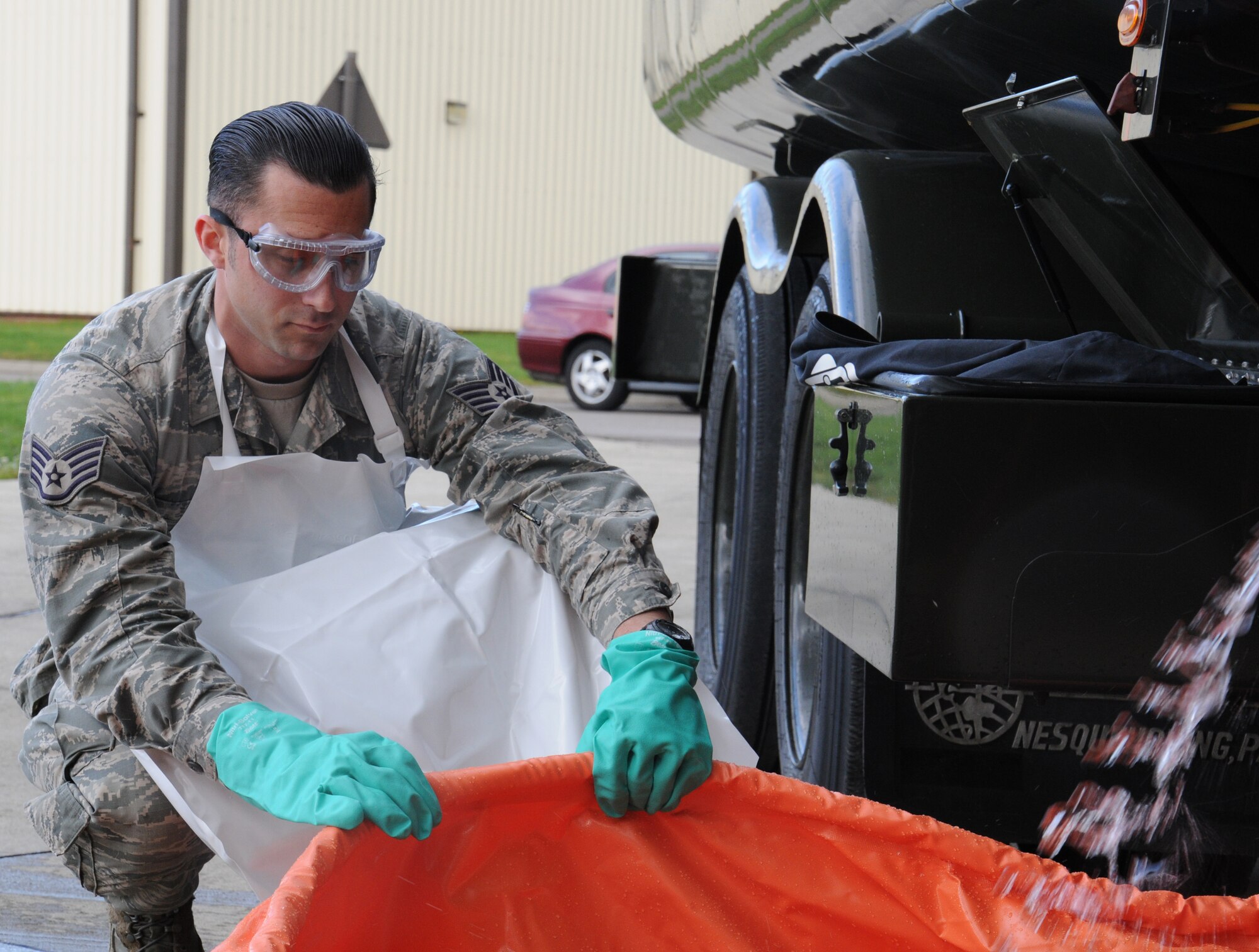 U.S. Air Force Staff Sgt. Zachary Kiniry, 100th Logistics Readiness Squadron Fuels training and support supervisor from Claremont, N.H., uses personal protective equipment Sept. 24, 2014, on RAF Mildenhall, England. Each spill kit housed on the fuel truck contains gloves, apron and goggles to protect the responding Airmen. (U.S. Air Force photo/Gina Randall/Released)