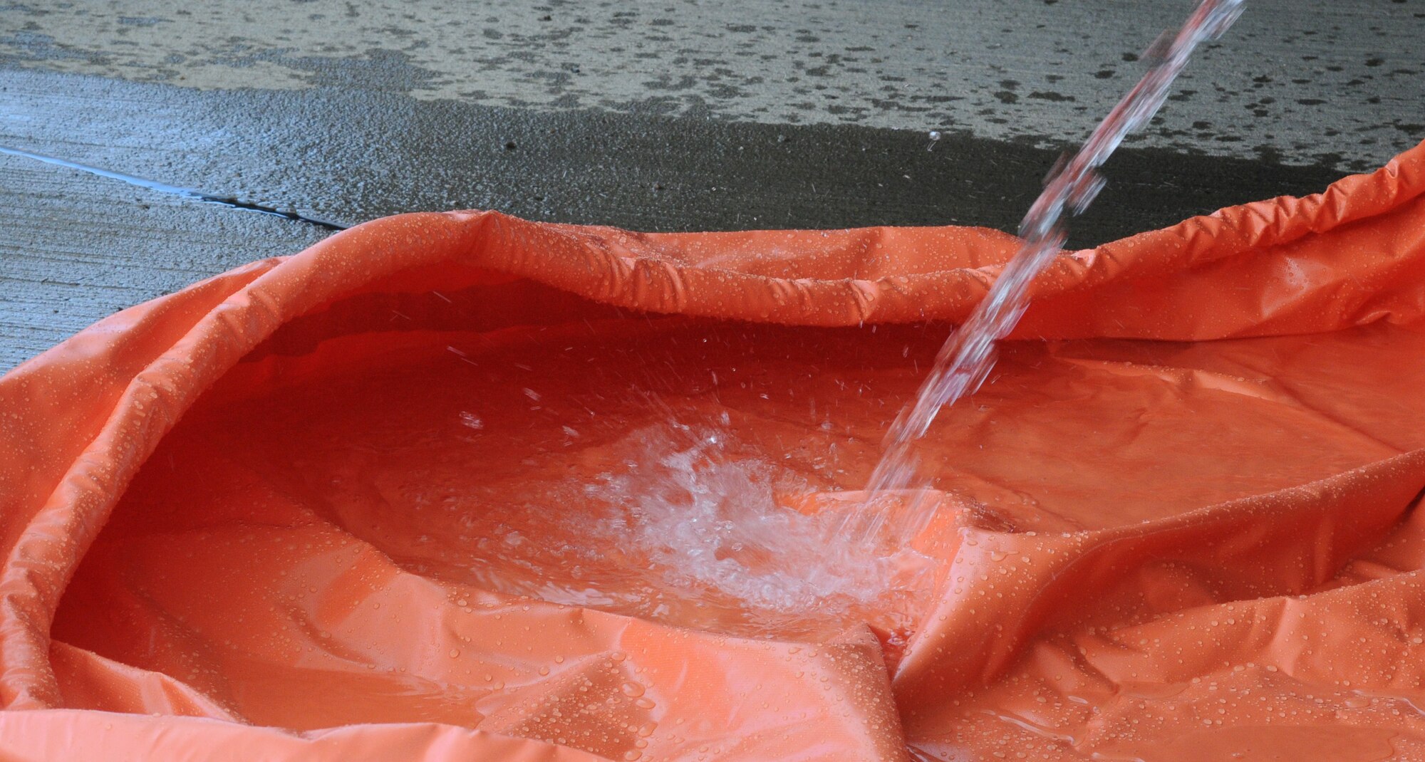 Water is hosed into a spill pool to demonstrate a fuel leak Sept. 24, 2014, on RAF Mildenhall, England. The spill pool is the first line of defense in containing a spill and the fuel contained can then be reused, saving the Air Force resources and money. (U.S. Air Force photo/Gina Randall/Released)