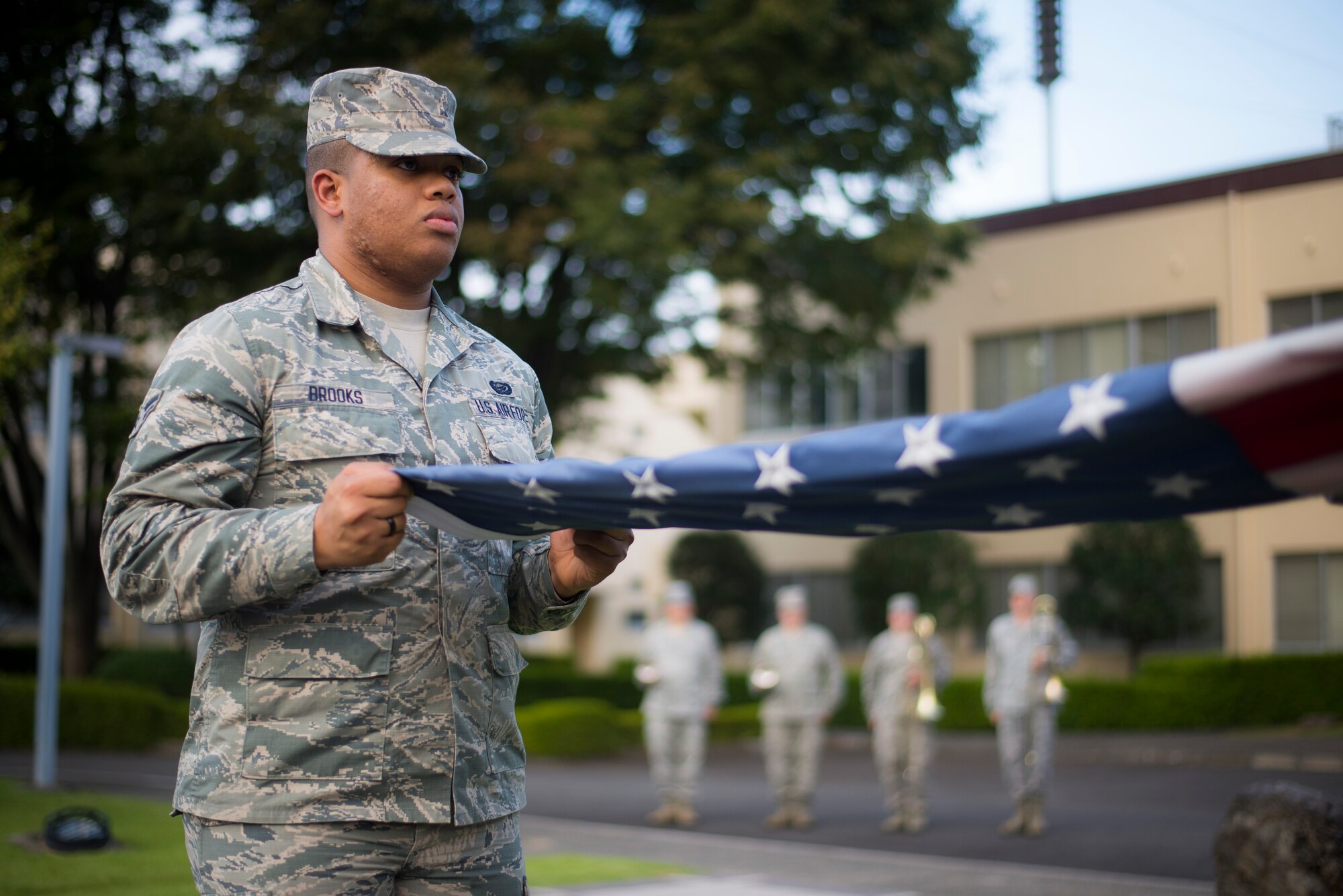 Airman 1st Class Christian Brooks, 374th Force Support Squadron, assists in folding the flag during a retreat ceremony at Yokota Air Base, Japan, Sept. 26, 2014. The retreat ceremony serves a twofold purpose. It signals the end of the official duty day as well as a ceremony for paying respect to the flag. (U.S. Air Force photo by Staff Sgt. Chad C. Strohmeyer)(Released)