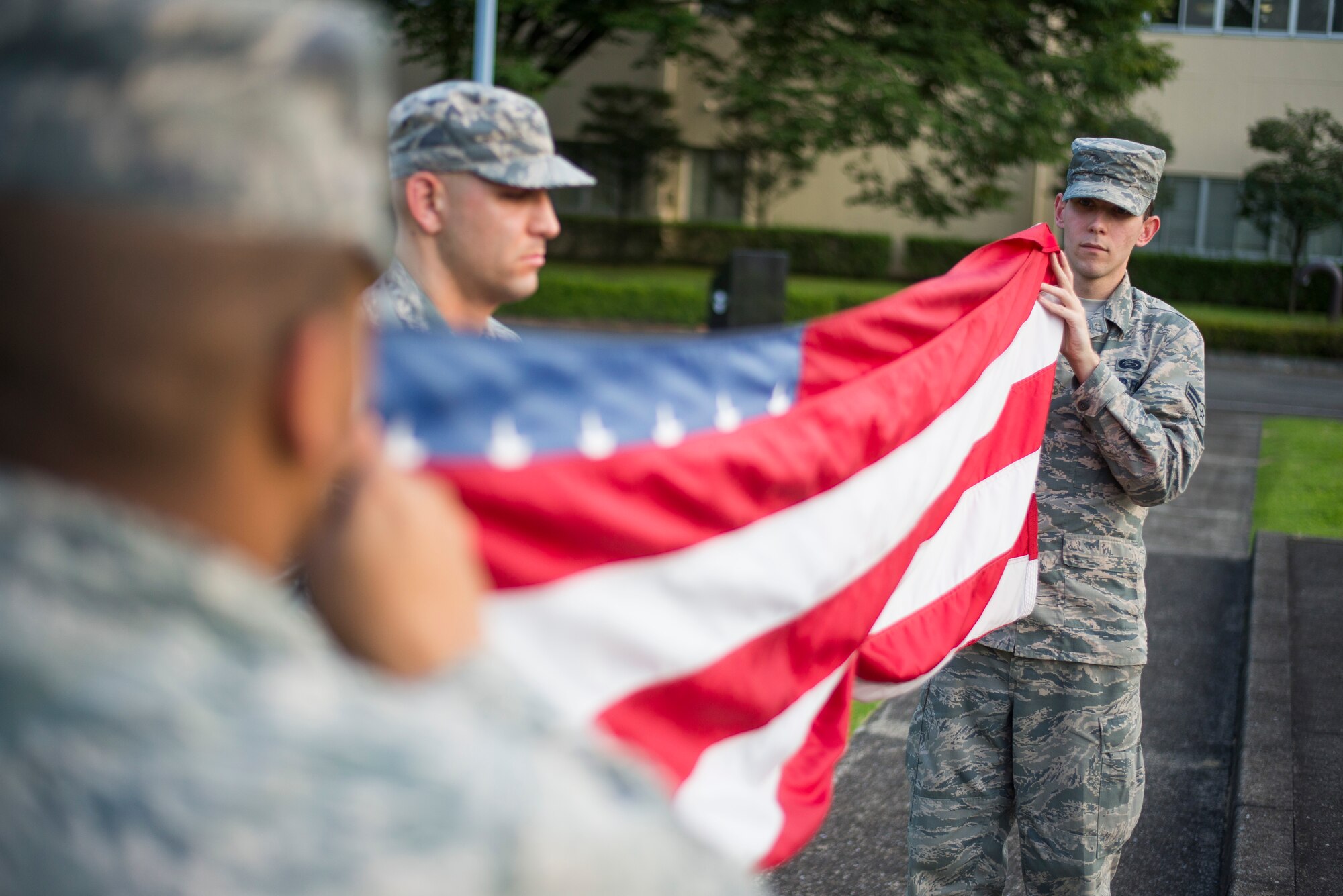 Members from the 374th Force Support Squadron fold the flag during a retreat ceremony at Yokota Air Base, Japan, Sept. 26, 2014. The retreat ceremony serves a twofold purpose. It signals the end of the official duty day as well as a ceremony for paying respect to the flag. (U.S. Air Force photo by Staff Sgt. Chad C. Strohmeyer)(Released)