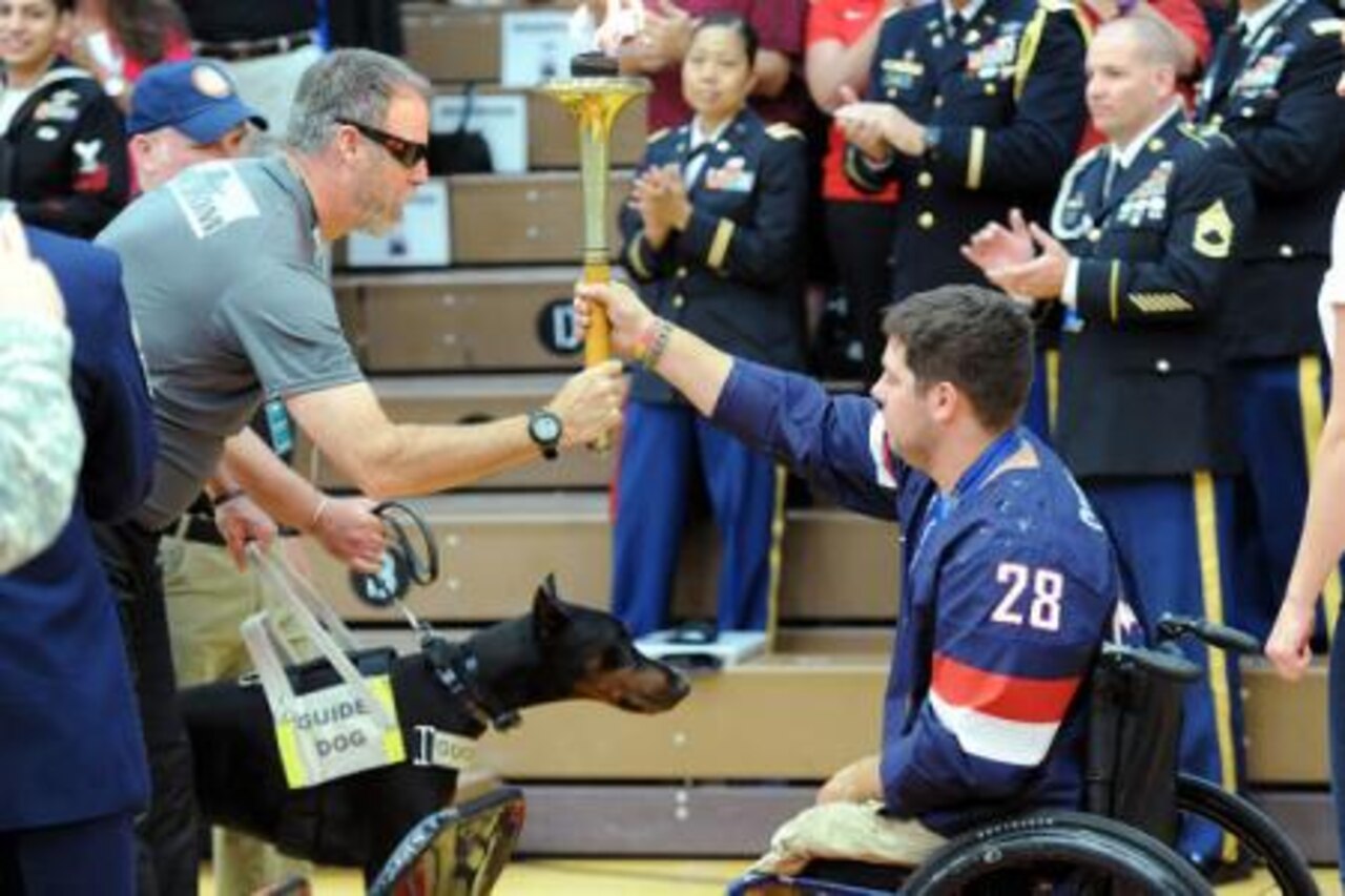 Army Sgt. 1st Class Doug Franklin of the Army Special Operations Command team passes the Olympic torch to retired Marine Corps Cpl. Paul Schaus, who is a gold medal Paralympian, during the opening ceremony for the 2014 Warrior Games at the Olympic Training Center in Colorado Springs, Colo., Sept. 28, 2014. U.S. Army photo by J.D. Leipold