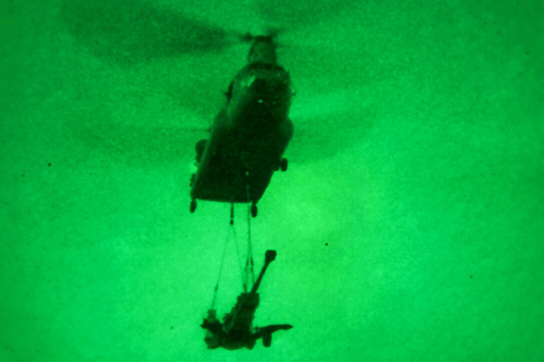 As seen through a night-vision device, a CH-47 Chinook helicopter lifts off to transport an M777A2 weapons system during slingload operations on Forward Operating Base Lightning in Afghanistan's Paktya province, Sept. 24, 2014.
