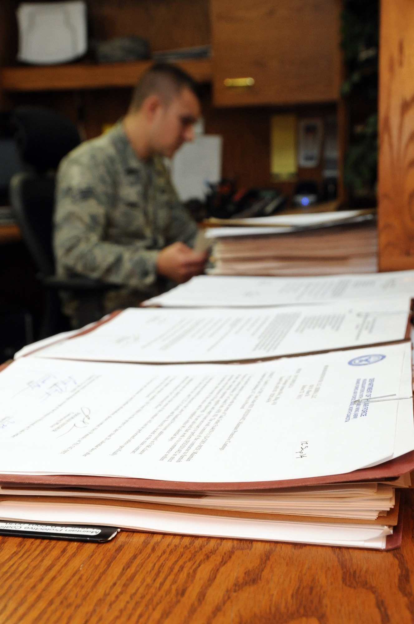 Senior Airman Alexander Ponusky, 319th Contracting Flight contract specialist, reviews paperwork in the 319th CONF office on Grand Forks Air Force Base, N.D., Sept. 25, 2014. The 319th CONF creates and oversees contracts ranging from small purchases of supplies to multimillion dollar construction projects. (U.S. Air Force photo/Staff Sgt. David Dobrydney)