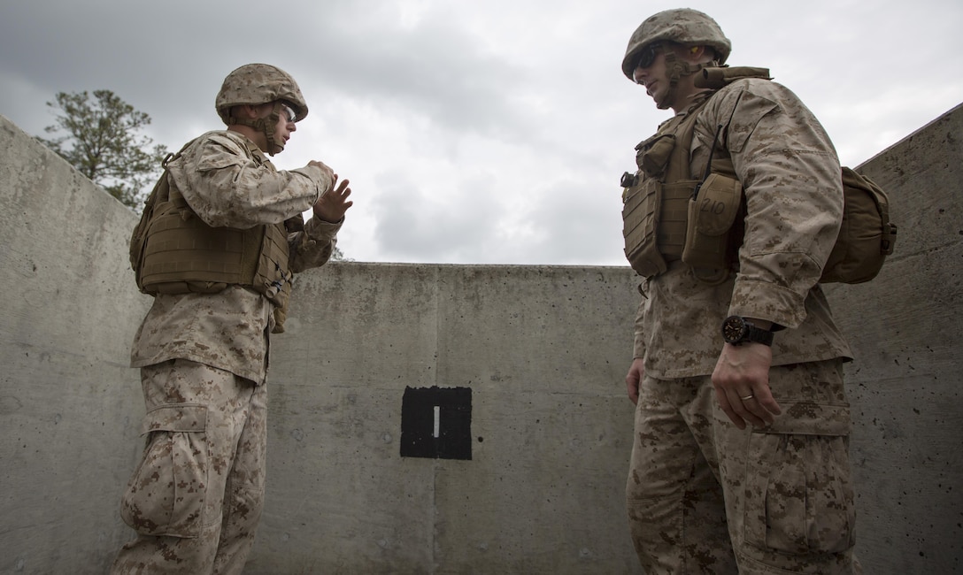 Corporal Michael Gould, right, a safety officer for the grenade range with Engineer Support Company, 8th Engineer Support Battalion, instructs Pfc. Kevin McNamara on how to remove the safety pins from the M67 fragmentation grenade before throwing it aboard Camp Lejeune, N.C. March 27, 2015. An instructor was placed in each of the four pits to guide the Marines on how to remove the grenade’s safety pins, properly throw the grenade and take cover after throwing it. 