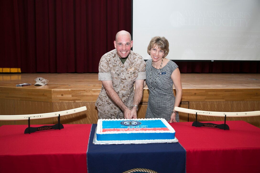 Col. Thomas A. Pecina, left, and Michelle McBride, right, pose for a photo as they cut a cake March 16 at the Camp Foster Community Center during an event commemorating the start of the Okinawa 2015 Active Duty Fund Drive for the Navy-Marine Corps Relief Society. The NMCRS provides financial relief to active duty and retired Marines and sailors as well as their eligible surviving family members through interest-free loans and grants. A large portion of those loans and grants are raised through the ADFD, which gives active duty military a chance to donate and help their fellow service members in need. Pecina is the commanding officer of Headquarters and Support Battalion, Marine Corps Installations Pacific-Marine Corps Base Camp Butler, Japan, and McBride is the director of the Navy-Marine Corps Relief Society, Okinawa office. 
