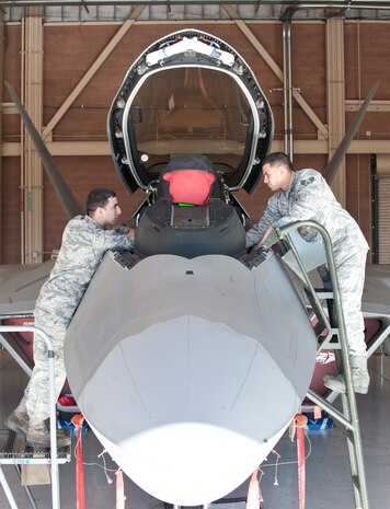 Senior Airmen Leonel and Anibal DeJesus-Martinez, both F-22 Raptor integrated avionics technicians assigned to 57th Aircraft Maintenance Squadron, work together on an F-22 at Nellis Air Force Base, Nev., March 25, 2015. The brothers have used their love of competition to push each other to do the best they can every day in their Air Force careers. (U.S. Air Force photo by Staff Sgt. Victoria Sneed)