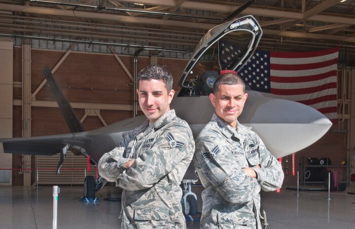 Senior Airmen Leonel and Anibal DeJesus-Martinez, both F-22 Raptor integrated avionics technicians assigned to the 57th Aircraft Maintenance Squadron, pose in front of an F-22 at Nellis Air Force Base, Nev., March 25, 2015. Leonel’s career has mirrored his older brother Anibal’s, only taking place a year later. (U.S. Air Force photo by Staff Sgt. Victoria Sneed)