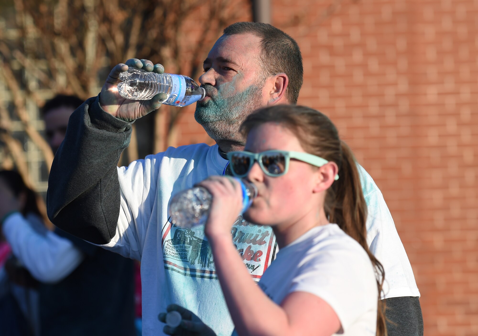 Run with Color 5k participants drink water after the event on Joint Base Andrews, Md., April 1, 2015. The Participants were covered in teal powder during the course.  More than 200 joint-service members attended the event. (U.S. Air Force photo/ Senior Airman Nesha Humes)