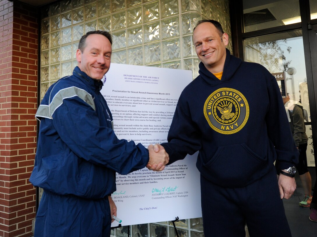 Col. Brad Hoagland, JBA/11th Wing commander, and Capt. Anthony Gilbert, Naval District of Washington commanding officer, shake hands after signing the Proclamation for Sexual Assault Awareness Month 2015 on Joint Base Andrews, Md., April 1, 2015. This year’s theme is, “Eliminate Sexual Assault: Know Your Part, Do Your Part.” (U.S. Air Force photo/ Senior Airman Nesha Humes) 