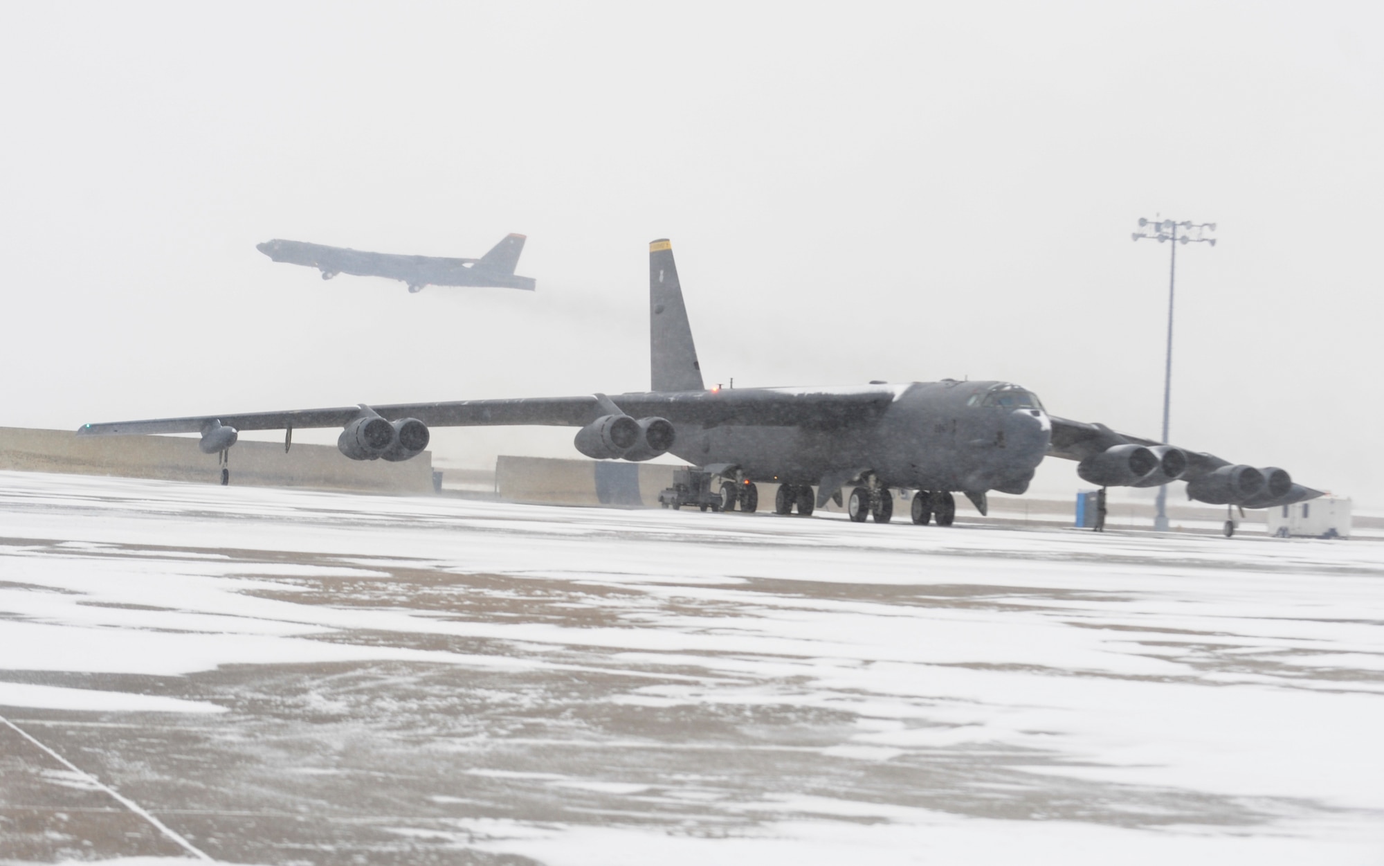 A B-52H Stratofortress waits on the flightline as another B-52 takes off during a rapid launch exercise on Minot Air Force Base, N.D., March 27, 2015. The exercise required fluid team work and cooperation between aircrews, crew chiefs and a variety of other base agencies. (U.S. Air Force photo/Senior Airman Stephanie Morris)