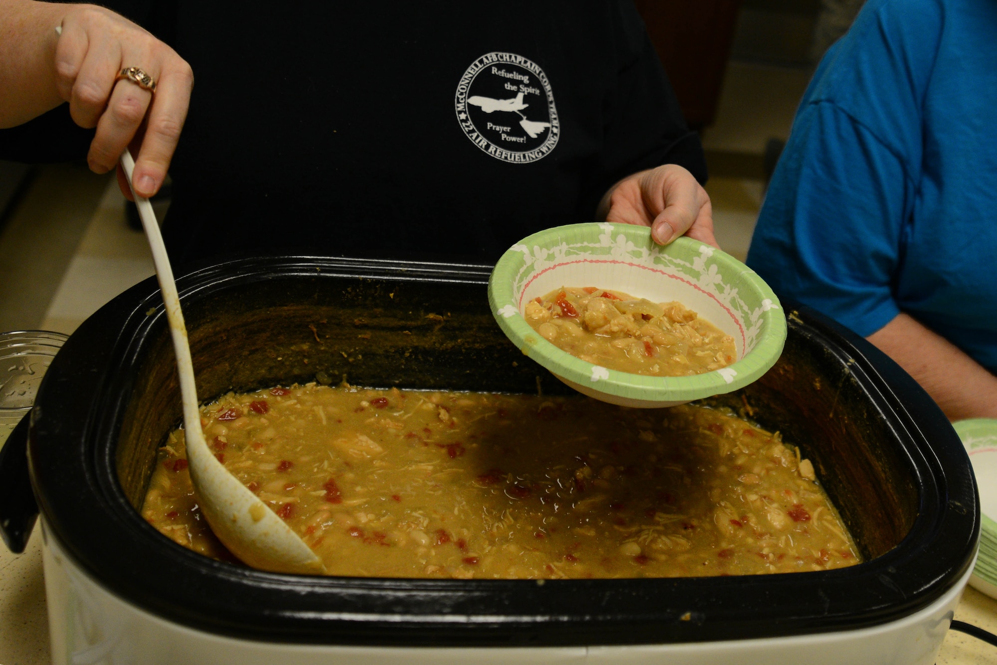 A chaplain assistant serves chicken chili during a chili lunch March 26, 2015, at McConnell Air Force Base, Kan. The McConnell Chapel sponsored the lunch to help boost morale and build bridges for the 22nd Aircraft Maintenace Squadron Airmen. (U.S. Air Force photo by Airman 1st Class Christopher Thornbury)