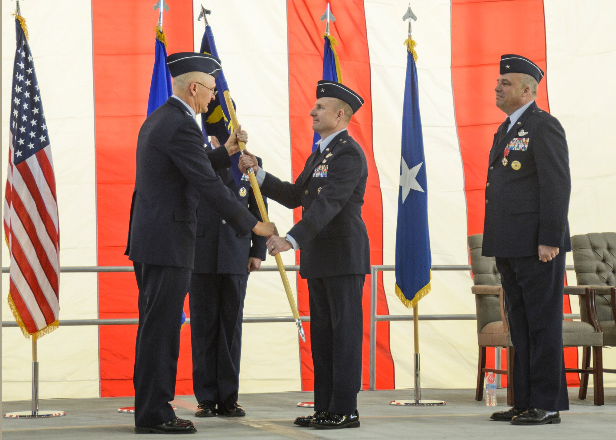 Maj. Gen. Arnold Bunch Jr., Air Force Test Center commander (left), presents the 412th Test Wing guidon to Brig. Gen. Carl Schaefer signifying the beginning of his new command at the 412th Test Wing change of command ceremony March 31 in Hangar 1600. Outgoing commander, Brig. Gen. Michael Brewer (right), will head to Wright-Patterson Air Force Base, Ohio, where he will be in charge of Air Force Materiel Command's Plans and Programs. (U.S. Air Force photo by Rebecca Amber)