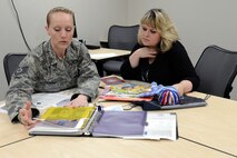 Tech. Sgt. Nalopa Hansen (left), 627th Force Support Squadron readiness NCO in charge, and Diana Burr, Servicemember and Family Readiness Center Air Force Aid officer, look through event plans March 31, 2015, on Joint Base Lewis-McChord, Wash. The S&FRC and Air Force Aid Society work together to provide services to Team McChord families. (U.S. Air Force photo/Senior Airman Rebecca Blossom)