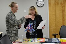 Tech. Sgt. Nalopa Hansen (left), 627th Force Support Squadron readiness NCO in charge, goes over the logistics of Operation KUDO with Diana Burr, Servicemember and Family Readiness Center Air Force Aid officer March 31, 2015, on Joint Base Lewis-McChord, Wash. Operation KUDO (Kids Understanding Deployment Operations) is one of the many events that are planned by the S&FRC. (U.S. Air Force photo/Senior Airman Rebecca Blossom)