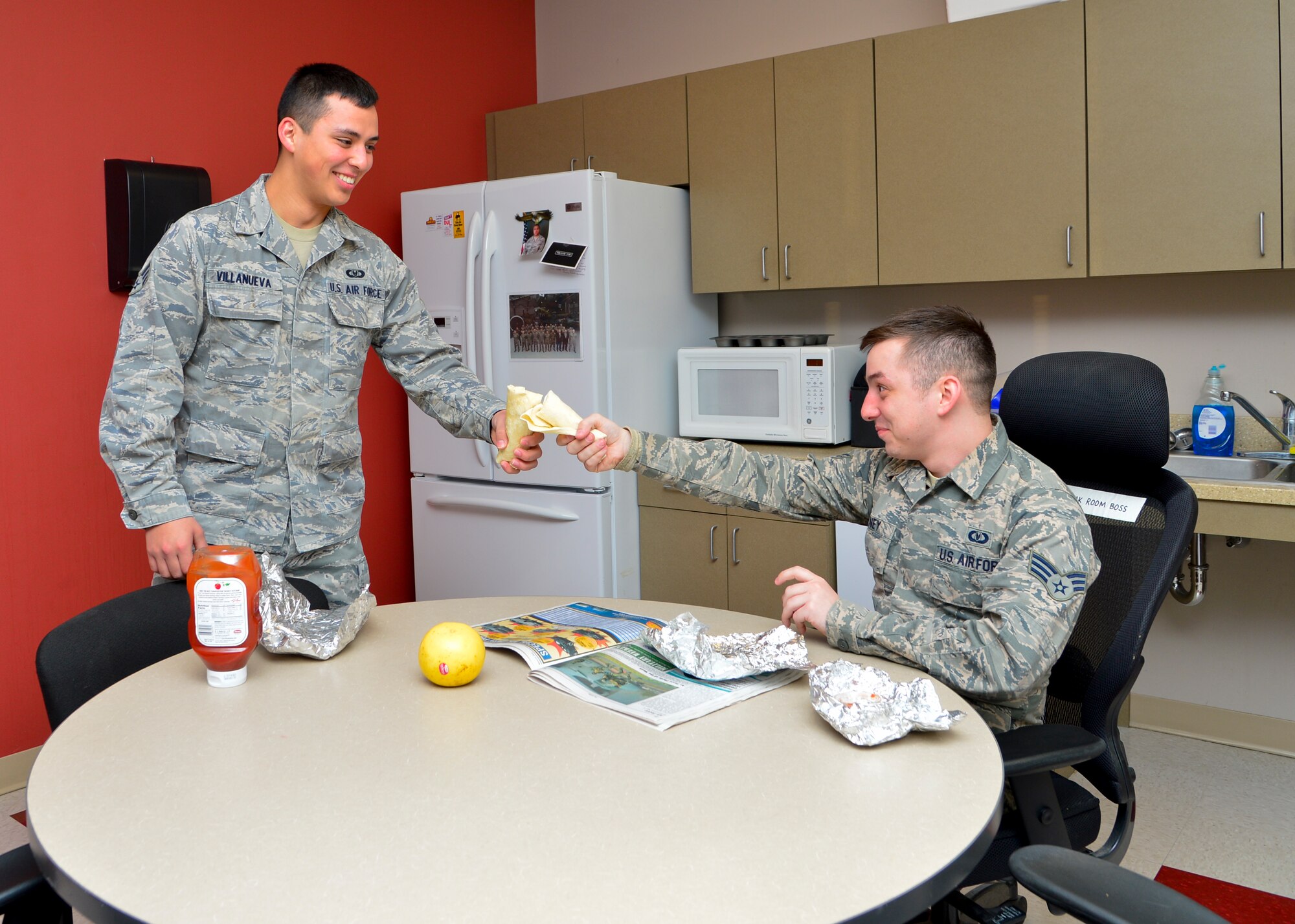 Senior Airman Gabriel Villanueva, left, and Senior Airman Casey Tierney, right, 436th Operations Support Squadron Aircrew Flight Equipment technicians, toast to free burritos April 1, 2015, at Dover Air Force Base, Del. The Dover AFB Top 3 organization provided more than 900 breakfast burritos to Airmen in the ranks of E-4 and below to boost morale across the base. (Air Force photo/Airman 1st Class William Johnson)