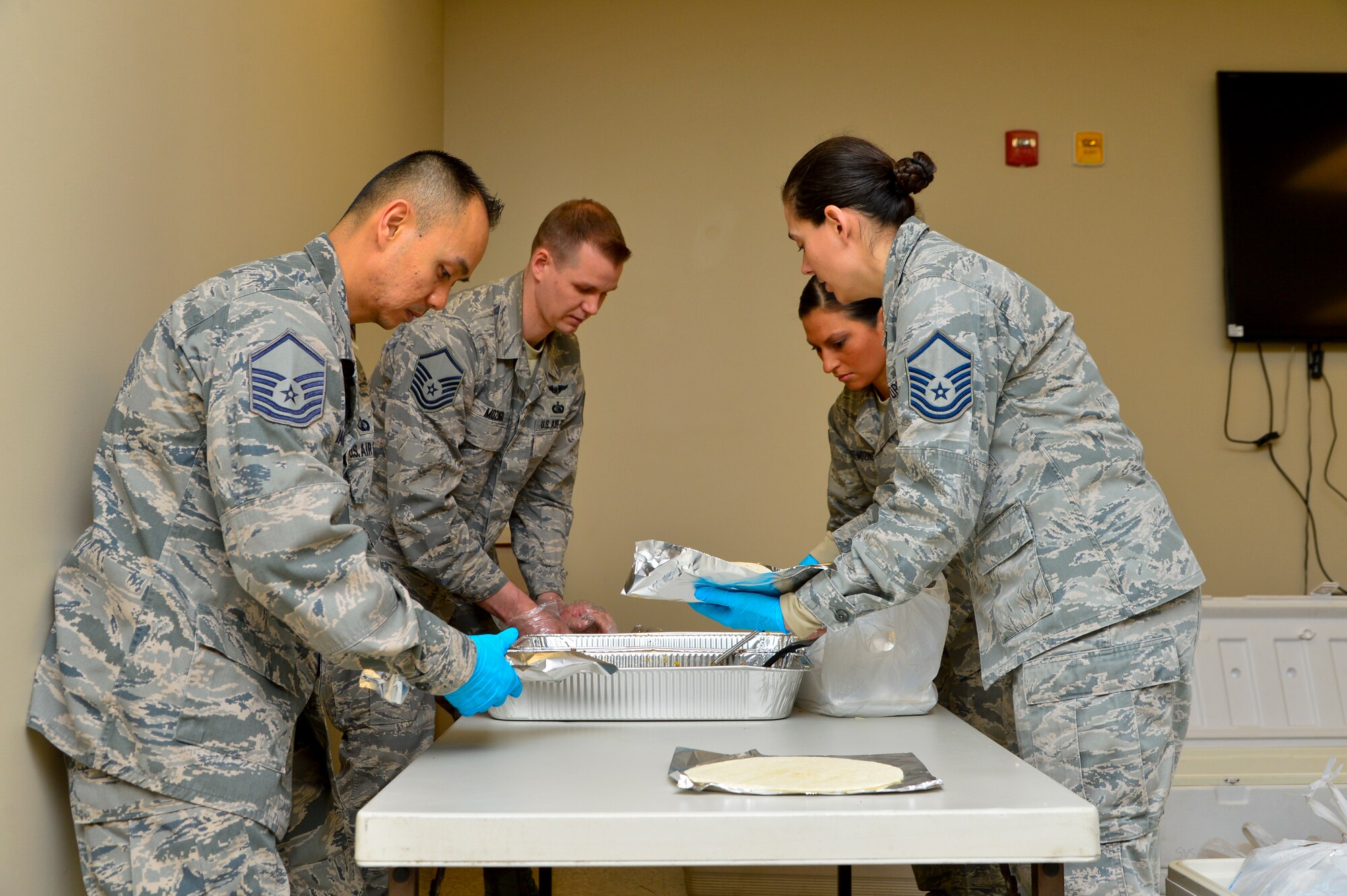 Members of the Dover Air Force Base Top 3 organization work to make more than 900 breakfast burritos April 1, 2015, at Dover AFB, Del. The Top 3 organization volunteered more than four hours to cook, make and distribute the burritos across the base to Airmen in the ranks of E-4 and below. (U.S. Air Force photo/Airman 1st Class William Johnson)