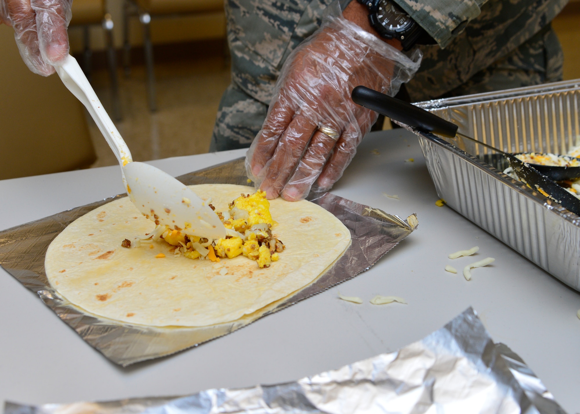 Master Sgt. Gregory Schindian, 436th Civil Engineer Squadron safety and security vehicle control officer, makes a breakfast burrito April 1, 2015, at Dover Air Force Base, Del. More than 900 burritos were made by the Dover AFB Top 3 organization and distributed across the base to Airmen in the ranks of E-4 and below to boost morale. (U.S. Air Force photo/Airman 1st Class William Johnson)
