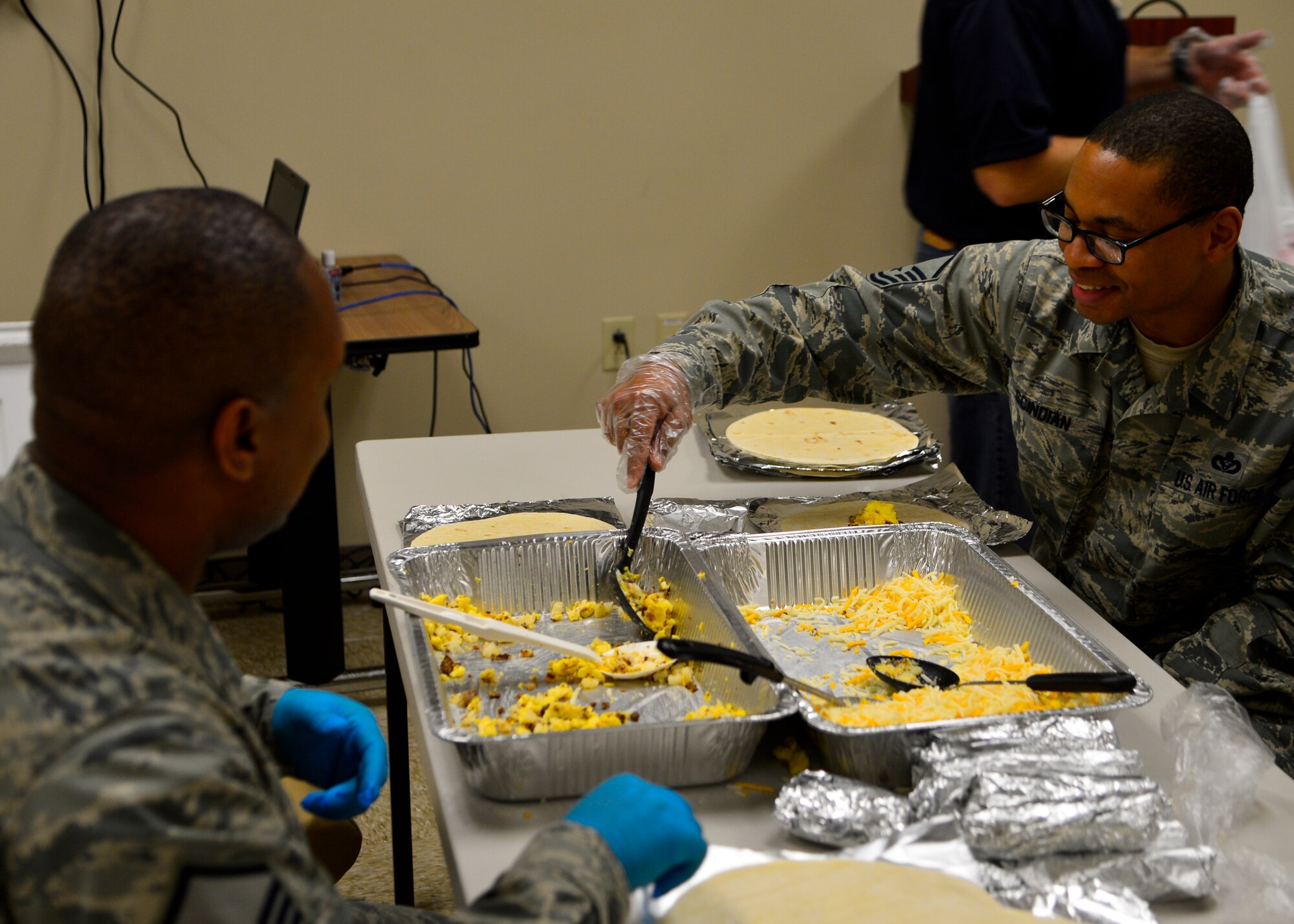 Master Sgt. Michael Heath, 436th Civil Engineer Squadron construction manager, left, and Master Sgt. Gregory Schindian, 436th CES safety and security vehicle control officer, right, make breakfast burritos April 1, 2015, at Dover Air Force Base, Del. The Dover AFB Top 3 organization made more than 900 burritos to give away to Airmen in the ranks of E-4 and below across the base. (U.S. Air Force photo/Airman 1st Class William Johnson)