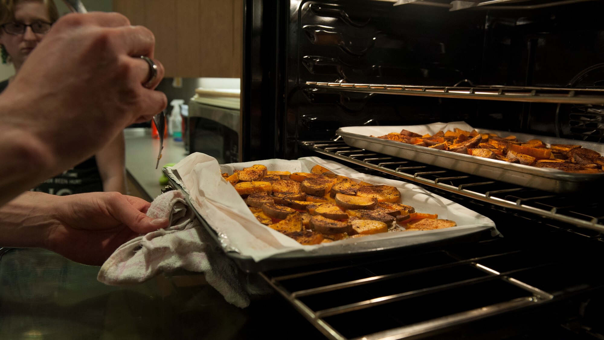 Jeffrey Moore, 436th Force Support Squadron, checks on the progress of baking sweet potatoes  March 31, 2015, at Dover Air Force Base, Del.The course teaches Airmen, who live in the dorms, how to cook healthy meals for themselves. (U.S. Air Force photo/Airman 1st Class Zachary Cacicia)