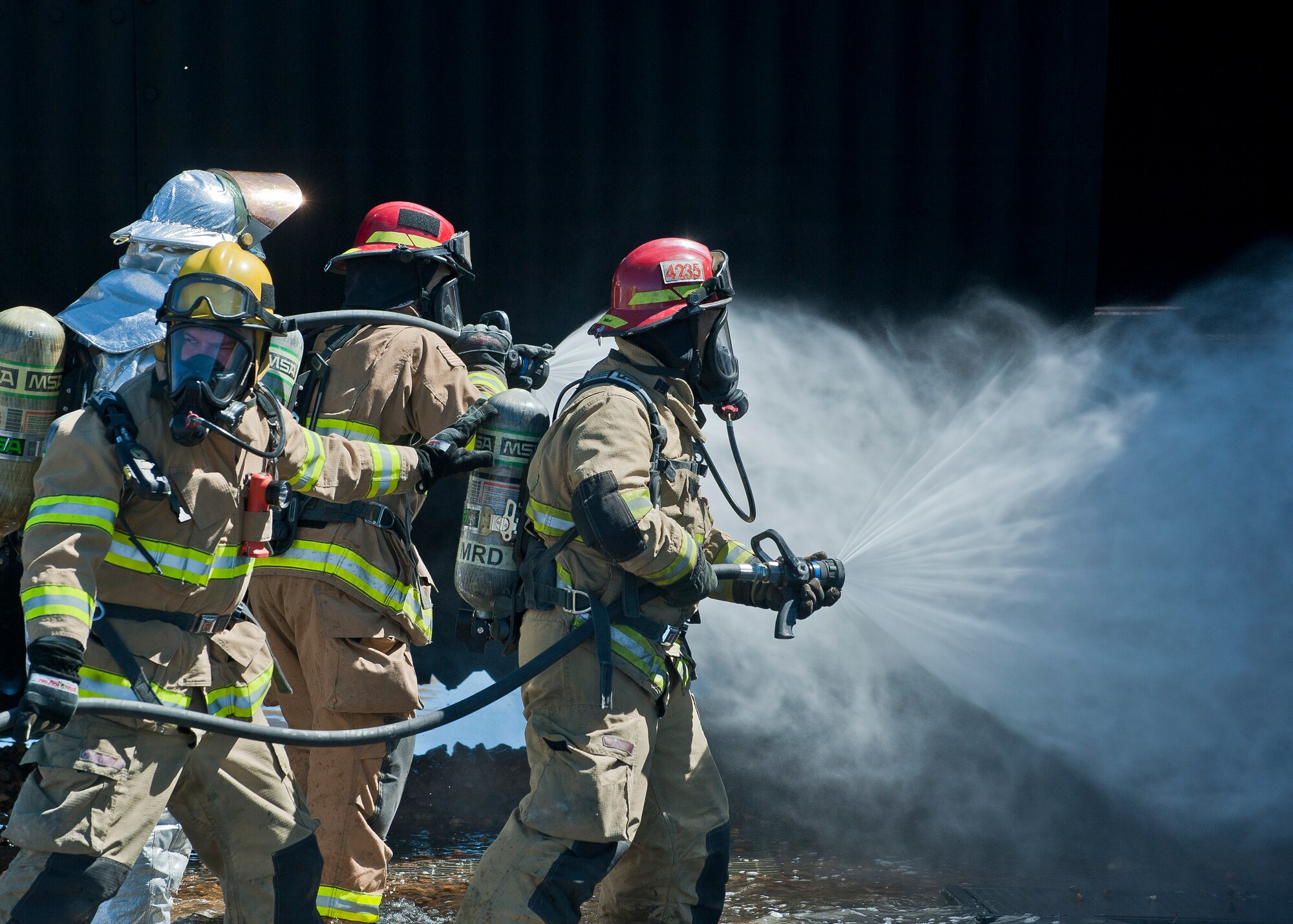 Firefighters from the Merced County Fire Department’s Castle Fire Station 62, Atwater, Calif., spray water on an aircraft during training at the burn pit on Nellis Air Force Base, Nev., March 27, 2015. The firefighters suppressed an aircraft fire with a hose attached to a rapid intervention vehicle, which can deliver 1,500 gallons of water per minute. (U.S. Air Force photo by Staff Sgt. Siuta B. Ika)