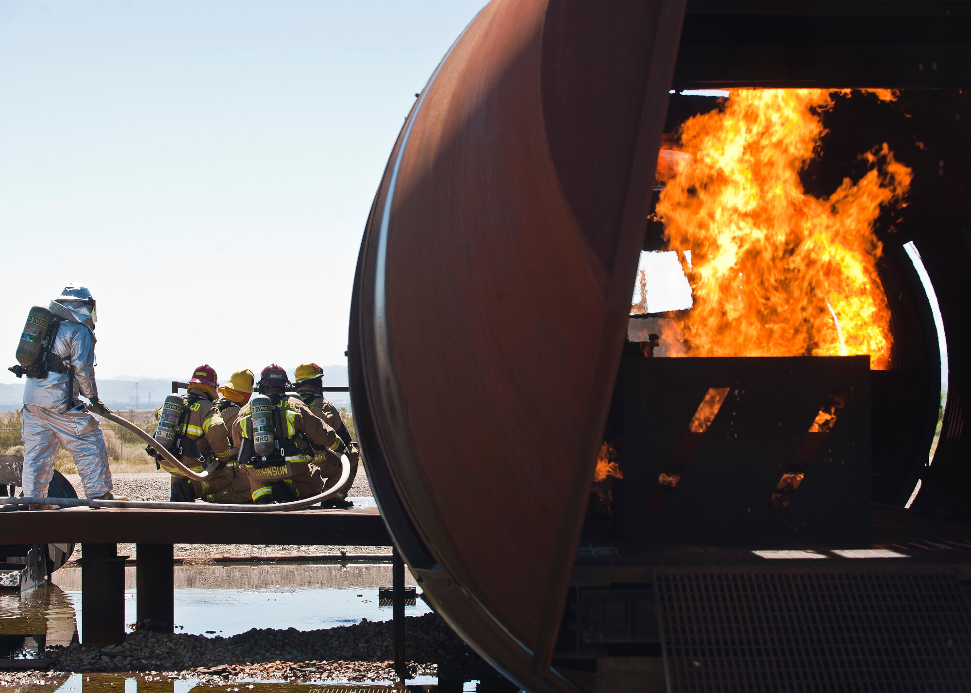 Firefighters from the Merced County Fire Department’s Castle Fire Station 62, Atwater, Calif., wait to breach the door of an aircraft during training at the burn pit on Nellis Air Force Base, Nev., March 27, 2015. MCFD firefighters extinguished interior and exterior aircraft fires under the supervision of the 99th Civil Engineer Squadron Fire Emergency Services Flight. (U.S. Air Force photo by Staff Sgt. Siuta B. Ika)
