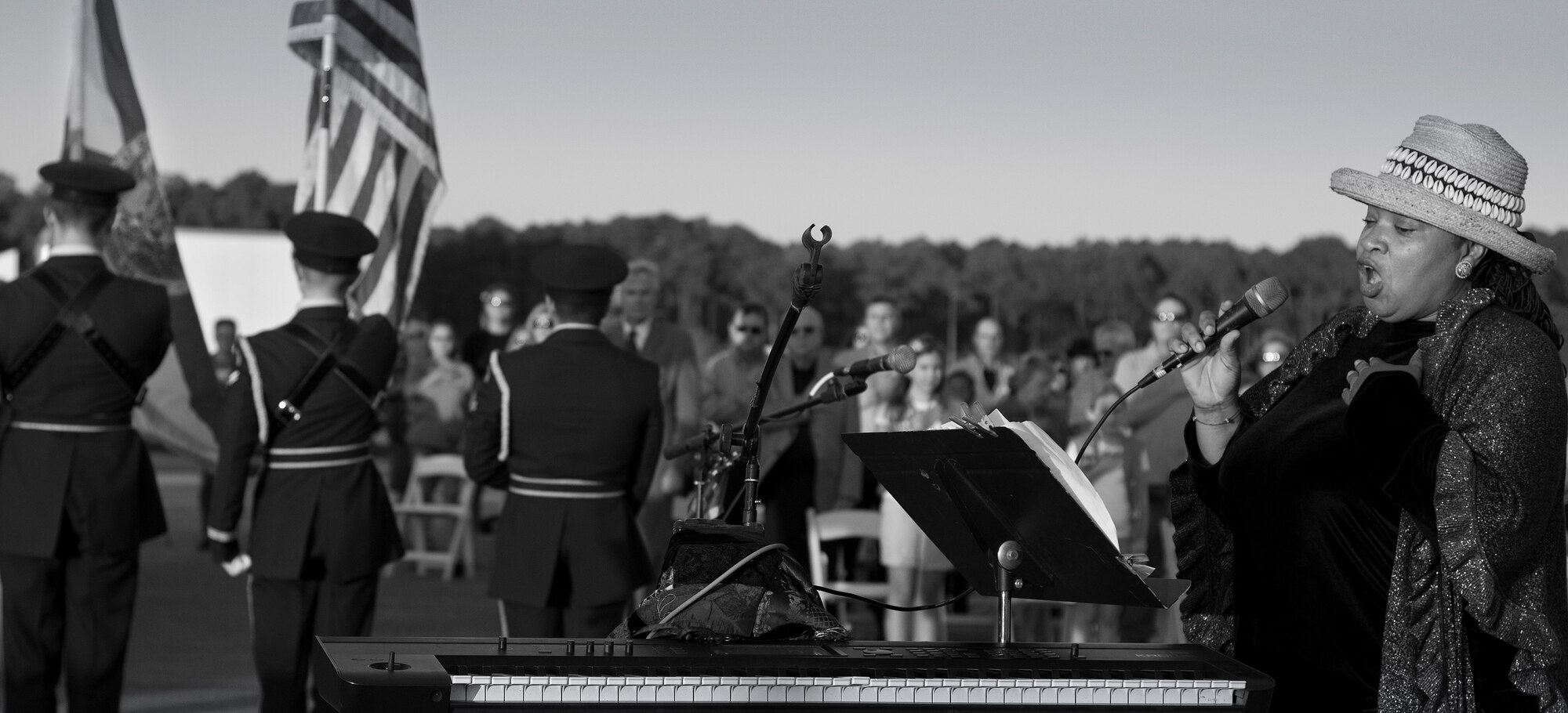 Cheryl Jones, a celebrity entertainer, sings the National Anthem while the Eglin Honor Guard posts the colors during the Black Hawk UH-60 memorial service March 31 at Destin Executive Airport, Fla.  Approximately 200 from the Destin community held a candlelight memorial service honoring the fallen servicemen in the Black Hawk UH-60 crash in Santa Rosa Sound on March 11.  (U.S. Air Force photo/Tech. Sgt. Jasmin Taylor)