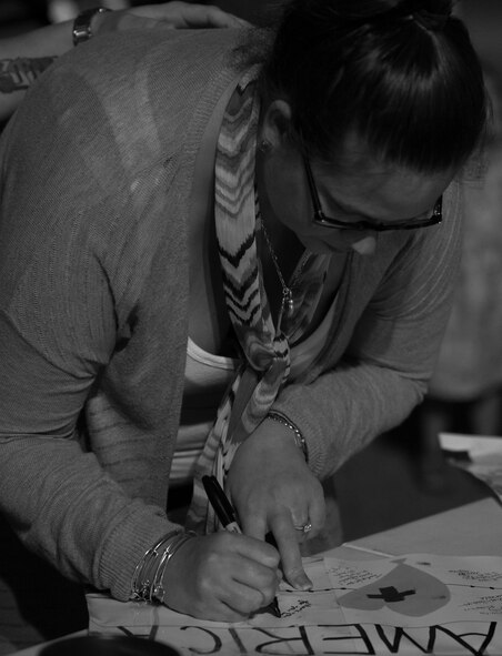 A member of the Destin community signs the banner during the Black Hawk UH-60 memorial service to remember the fallen servicemen March 31 at Destin Executive Airport, Fla.  Approximately 200 from the Destin community held a candlelight memorial service honoring the fallen servicemen in the Black Hawk UH-60 crash in Santa Rosa Sound on March 11.  (U.S. Air Force photo/Tech. Sgt. Jasmin Taylor)