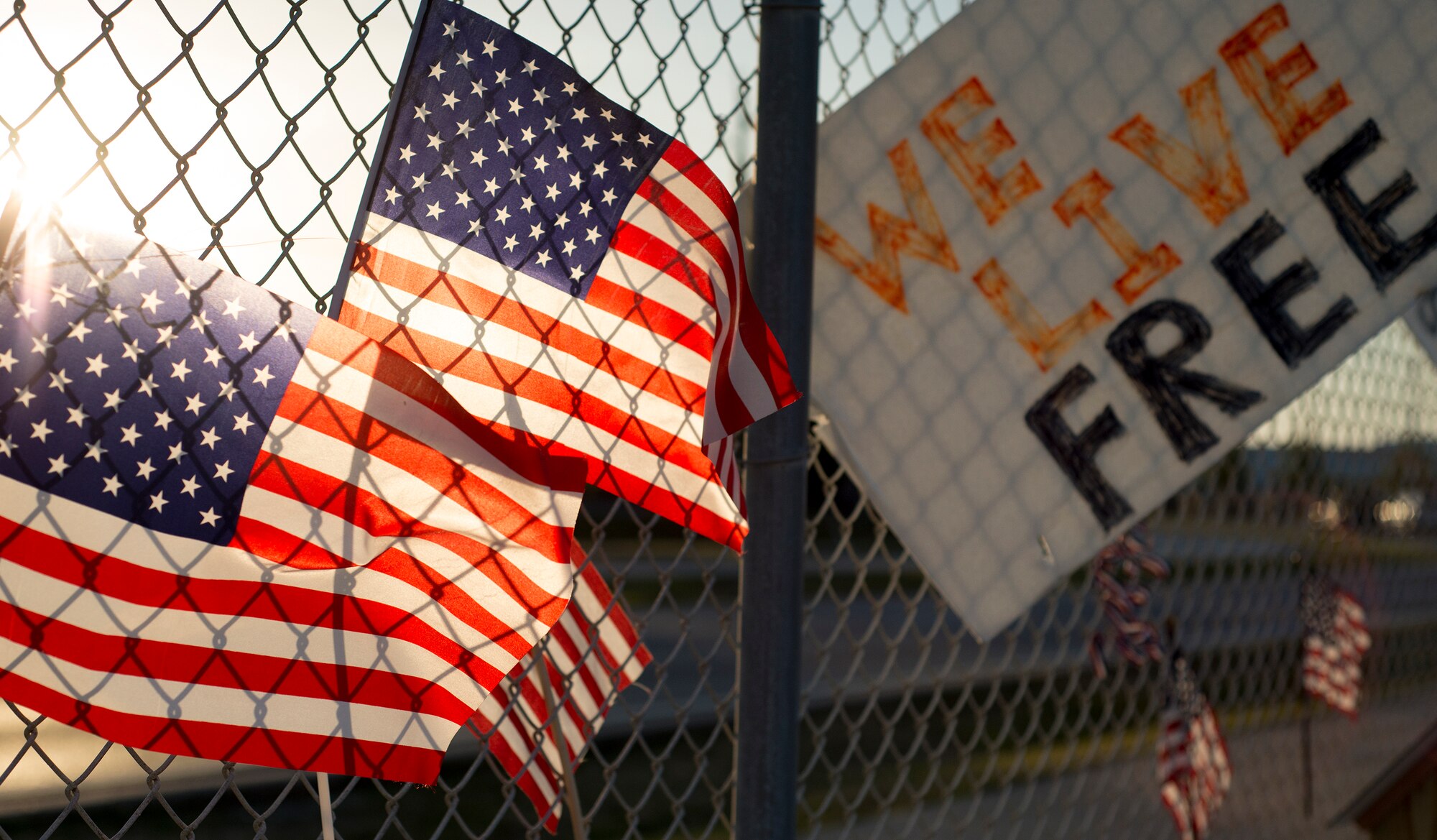 Members of the Destin community place flags and signs on the fence to remember the fallen servicemen March 31 at Destin Executive Airport, Fla.  The Destin community held a candlelight memorial service honoring the fallen servicemen in the Black Hawk UH-60 crash in Santa Rosa Sound on March 11.  (U.S. Air Force photo/Tech. Sgt. Jasmin Taylor)