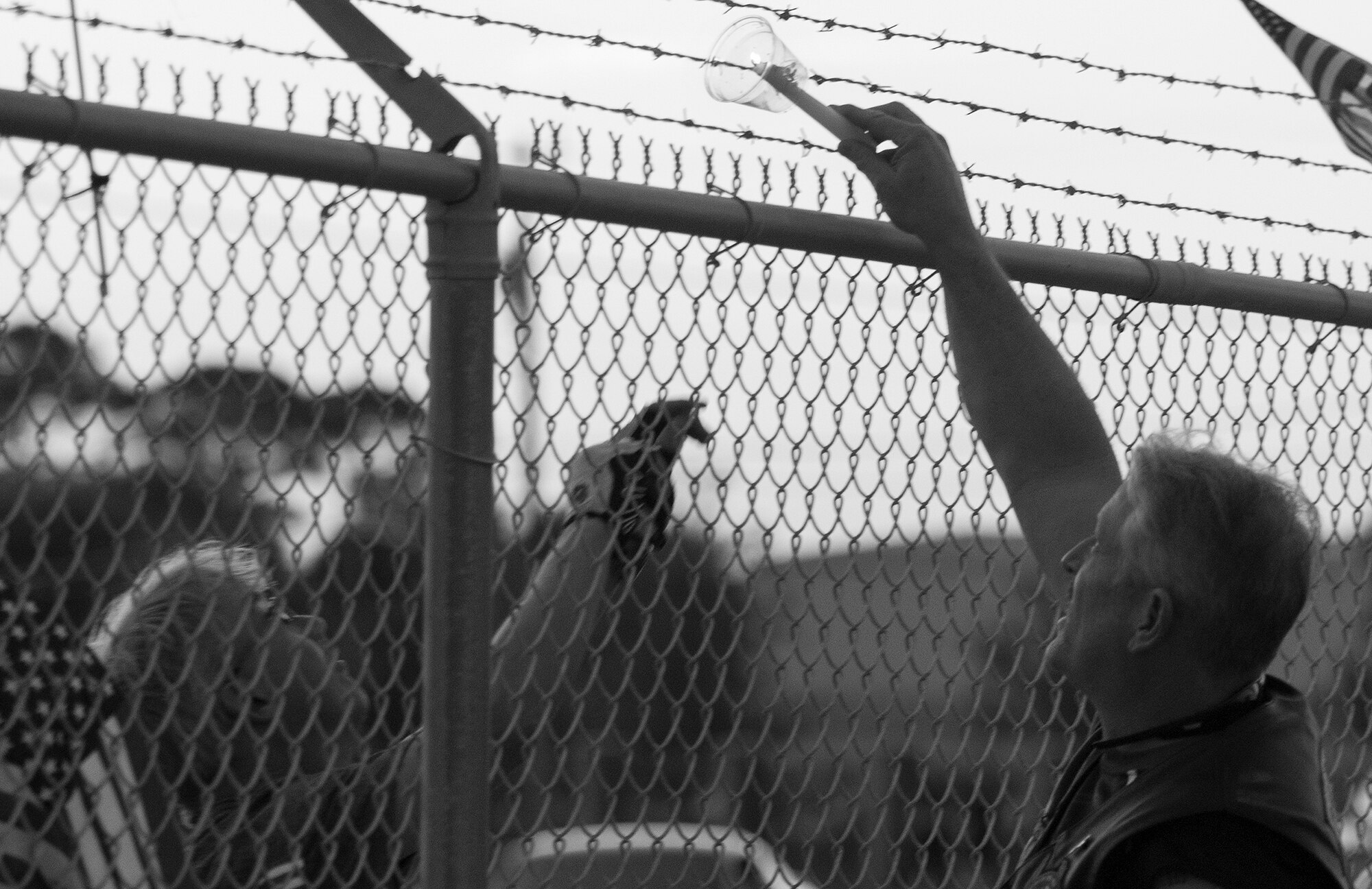 A flame is passed to those on the other side of the fence so no one is left out of the memorial ceremony to remember the fallen servicemen March 31 at Destin Executive Airport, Fla.  Approximately 200 from the Destin community held a candlelight memorial service honoring the fallen servicemen in the Black Hawk UH-60 crash in Santa Rosa Sound on March 11.  (U.S. Air Force photo/Tech. Sgt. Jasmin Taylor)