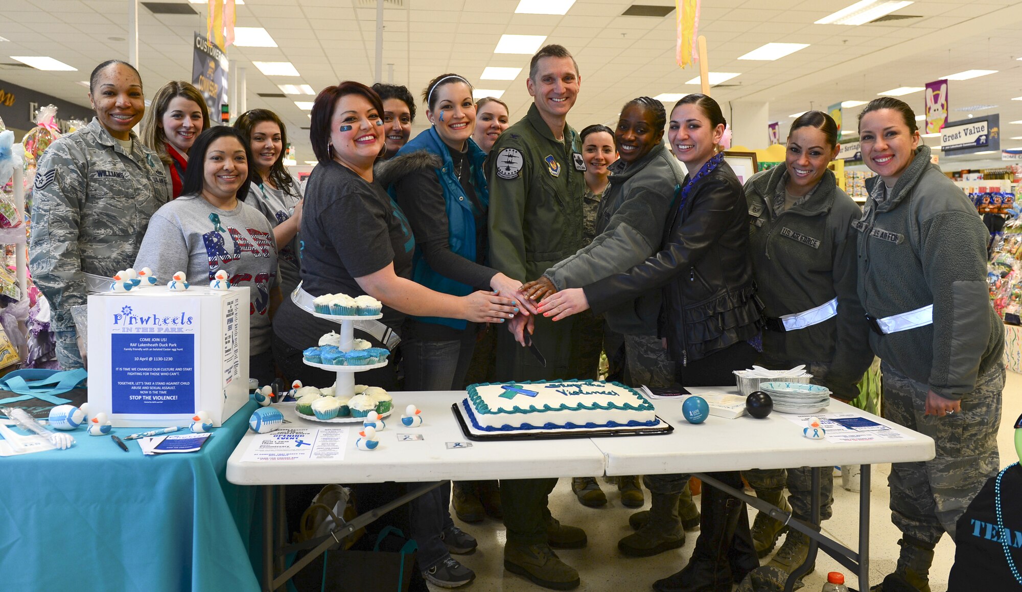 Col. Scottie Zamzow, 48th Operations Group commander, and the Sexual Assault Prevention and Response team cut the cake to kick off Sexual Assault and Child Abuse Awareness Month at the commissary on Royal Air Force Lakenheath, England, April 1, 2015. This annual observance highlights the efforts that all military services take to combat these crimes and promote prevention through special activities and public education. (U.S. Air Force photo by Airman 1st Class Dawn M. Weber/Released)