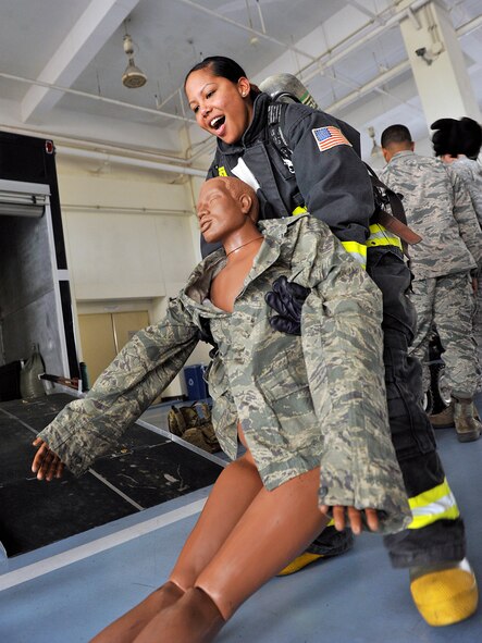 U.S. Air Force 2nd Lt. Lyneth Battle, 18th Munitions Squadron materiel flight commander, carries a training mannequin at the 18th Civil Engineer Squadron fire station during the Model Program on Kadena Air Base, Japan, March 25, 2015. The Model Program allows company grade officers to interact and train with members of different units allowing them to better function in leadership roles in their respective units. (U.S. Air Force photo by Naoto Anazawa)