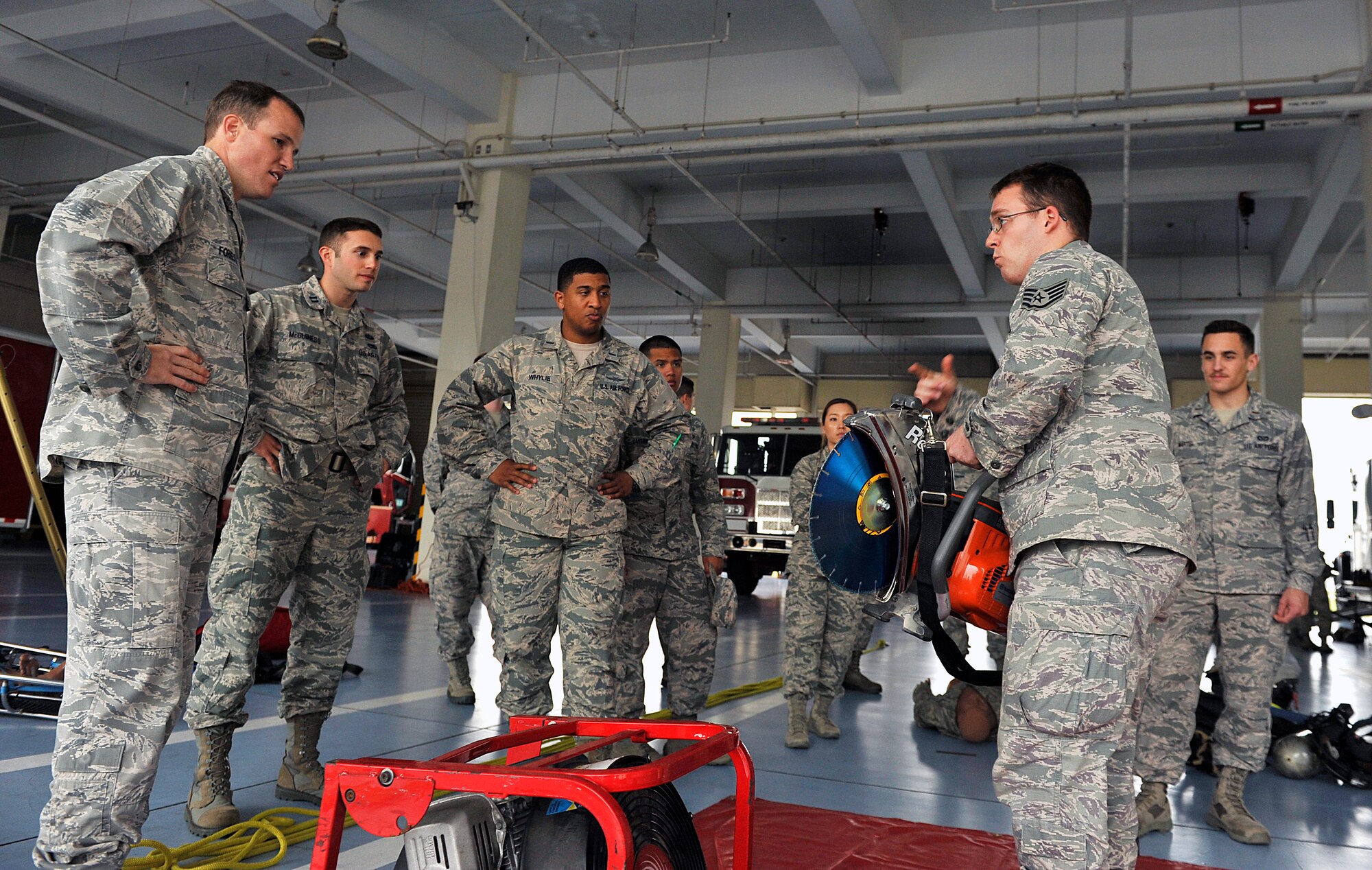U.S. Air Force Staff Sgt. Craigery Hassinger, 18th Civil Engineer Squadron Fire Department crew chief, explains to company grade officers the purpose of a K970 rescue saw, which the fire department uses for cutting obstacles during the Model Program on Kadena Air Base, Japan, March 25, 2015. The Model Program was created to accomplish three objectives; give CGOs a broader view of their mission, influence networking between CGOs of different Air Force specialty codes and to allow mentoring time between commanders and CGOs. (U.S. Air Force photo by Naoto Anazawa)