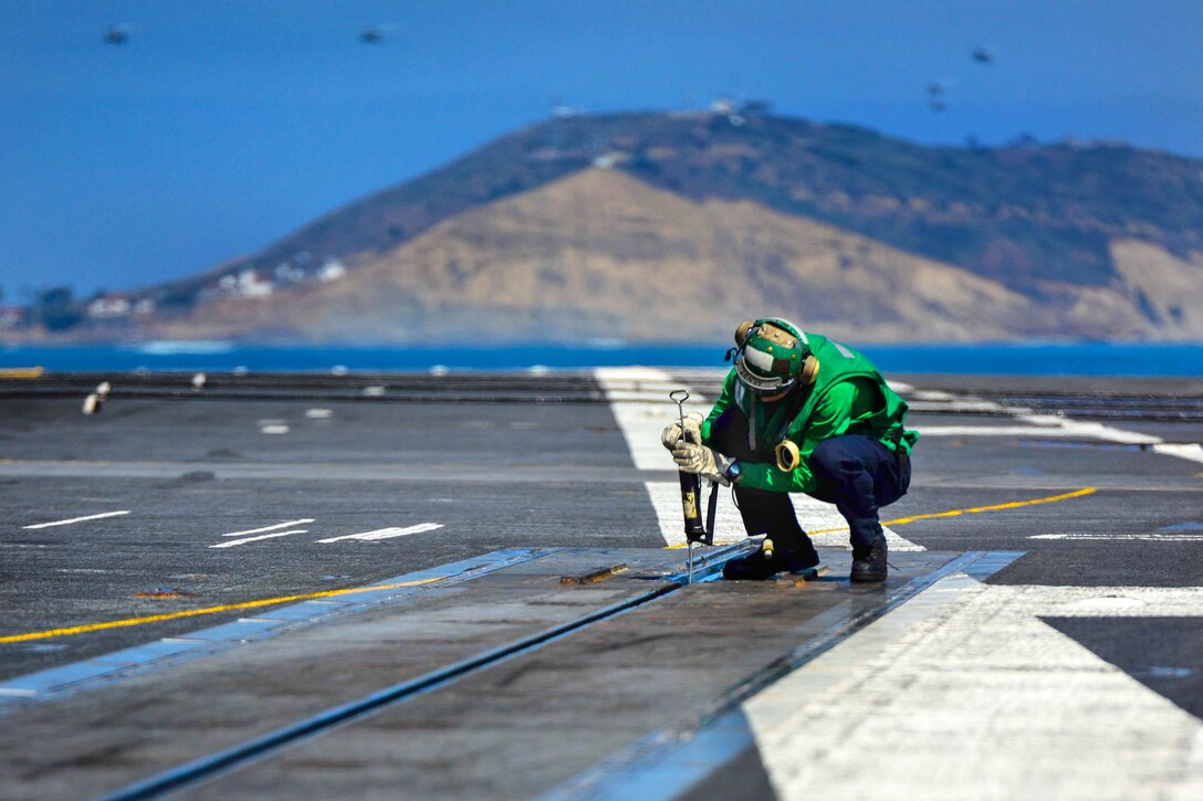 U.S. Navy Petty Officer 3rd Class Chadwick Arndt greases a catapult track in preparation for the launching of aircraft aboard USS John C. Stennis in the Pacific Ocean, March 30, 2015. Arndt is an aviation boatswain's mate equipment.