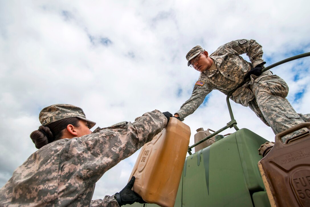 Army Spc. Michael Patlan, right, hands down a gas can to Army Cpl. Christelle Arriaga during a vehicle recovery operation on Camp Bullis, Texas, March 22, 2015. Patlan and 
Arriaga are assigned to the 277th Engineer Company.  
