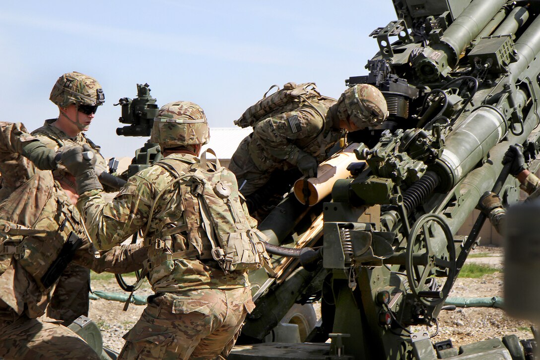 U.S. artillerymen load a round into an M777A2 howitzer to conduct ...