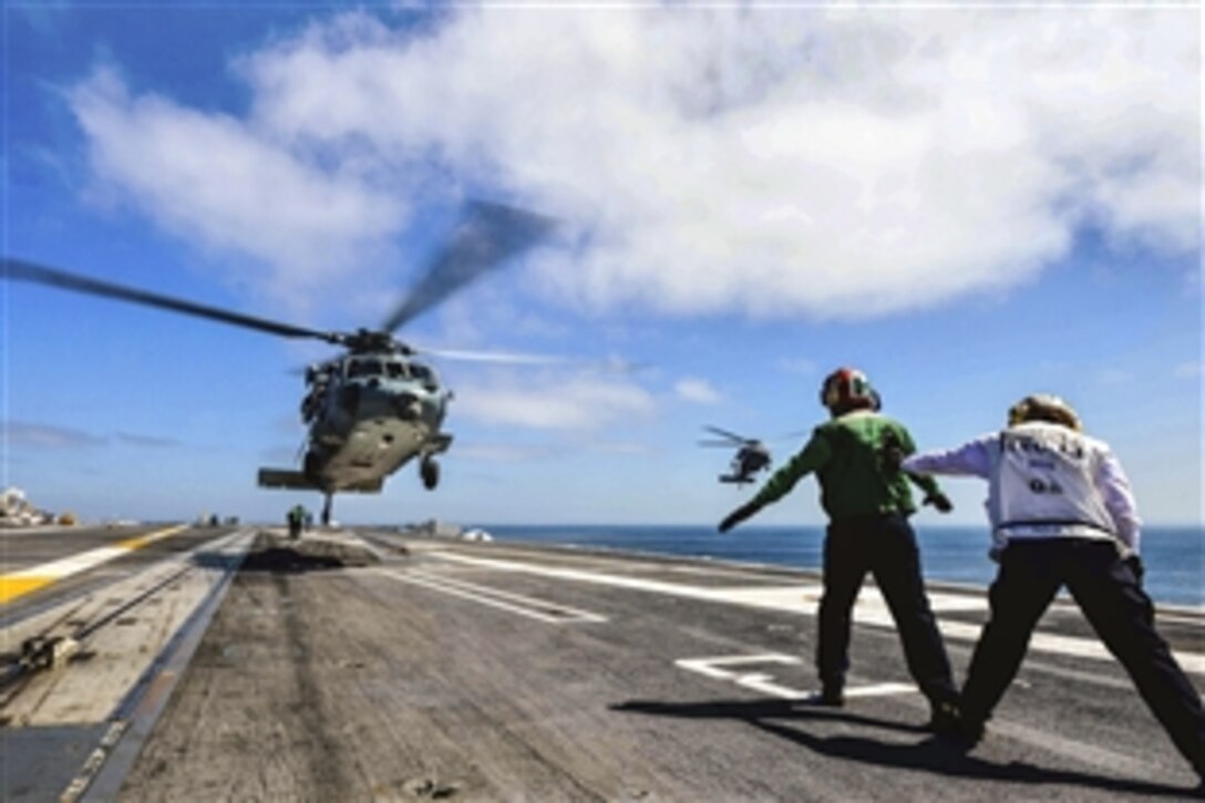 U.S. Navy Seaman Brett Holland and Petty Officer 2nd Class Michealyn Alfaro direct an MH-60S Knight Hawk helicopter as it touches down on the USS John C. Stennis during carrier qualifications in the Pacific Ocean, March 30, 2015. Holland is an aviation machinist's mate airman and Alfaro is an aviation electronics technician.