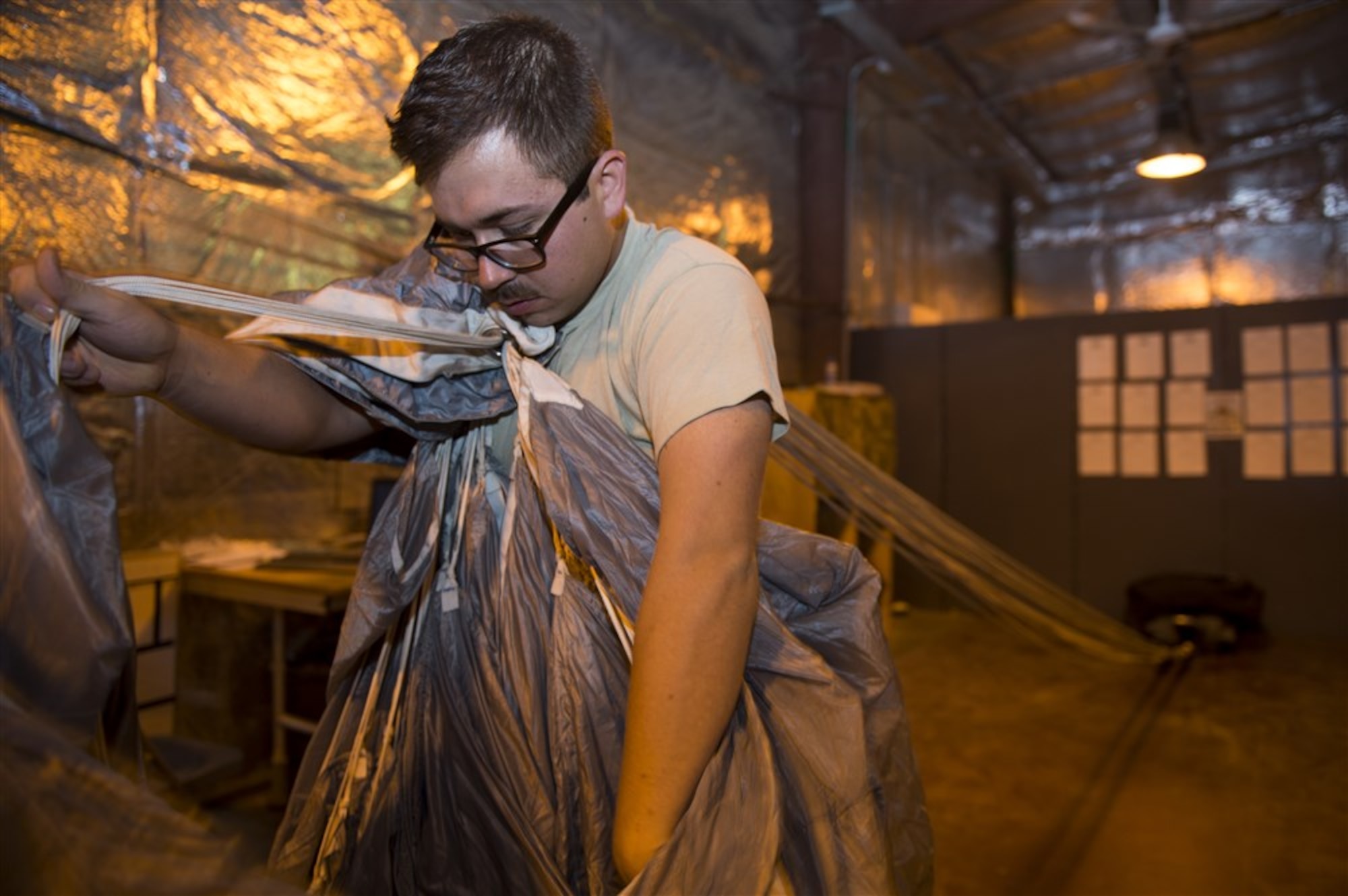 Senior Airman Dwain Miller carefully stacks the folds of a parachute during packing, at Camp Lemonnier, Djibouti, March 26, 2015. Miller, an 82nd Expeditionary Rescue Squadron Aircrew Flight Equipment rigger, ensures that each fold overlaps the last, allowing the correct deployment of the chute. (U.S. Air Force photo/Staff Sgt. Carlin Leslie)