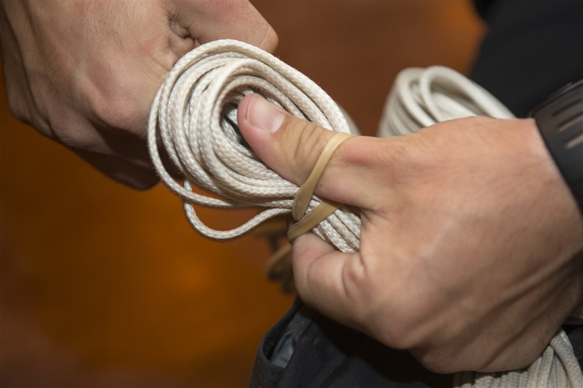 Taut suspension lines are secured to the outside of the chute on Camp Lemonnier, Djibouti, March 26, 2015. Rubber bands are used to provide the correct amount of tension for parachute deployment. (U.S. Air Force photo/Staff Sgt. Carlin Leslie)