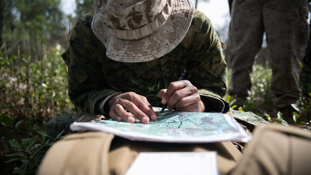 A Marine with Golf Company, 2nd Battalion, 2nd Marine Regiment, plots his first land navigation point during a land navigation exercise aboard  Camp Lejeune, N.C., March 30, 2015. The distance between each point ranged from two to six kilometers in a woodland set environment. 