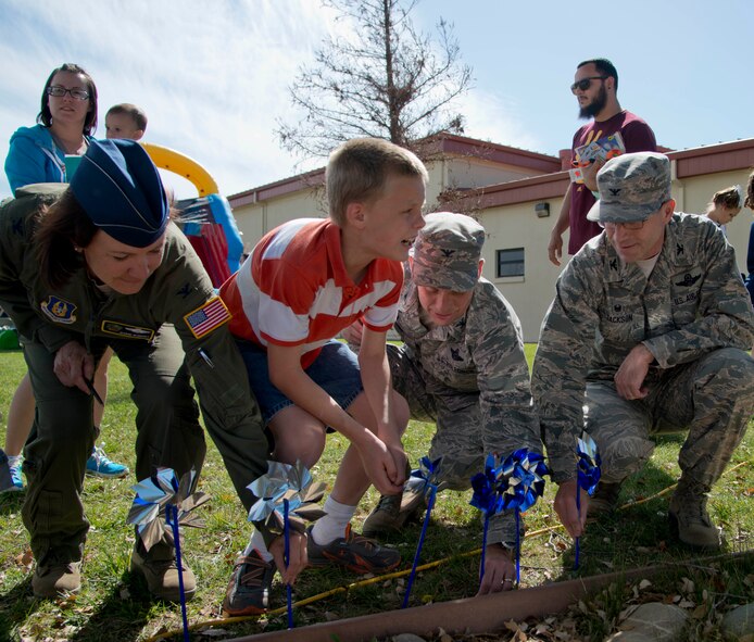 From right to left, Col. Joel Jackson, 60th Air Mobility Wing commander, Col. Matthew Burger, 349th Air Mobility Wing commander, and Lt. Col. Jeanine McAnaney, representing the 621st Contingency Response Wing commander, plant pinwheels with children at the Family Fun Fest in the Airman and Family Readiness Center parking lot on Travis Air Force Base, Calif., April 1. The pinwheel garden raises awareness for child abuse awareness month. Some communities use the pinwheels to represent the number of children affected by child abuse. (U.S. Air Force photo/Senior Airman Nicole Leidholm) 
