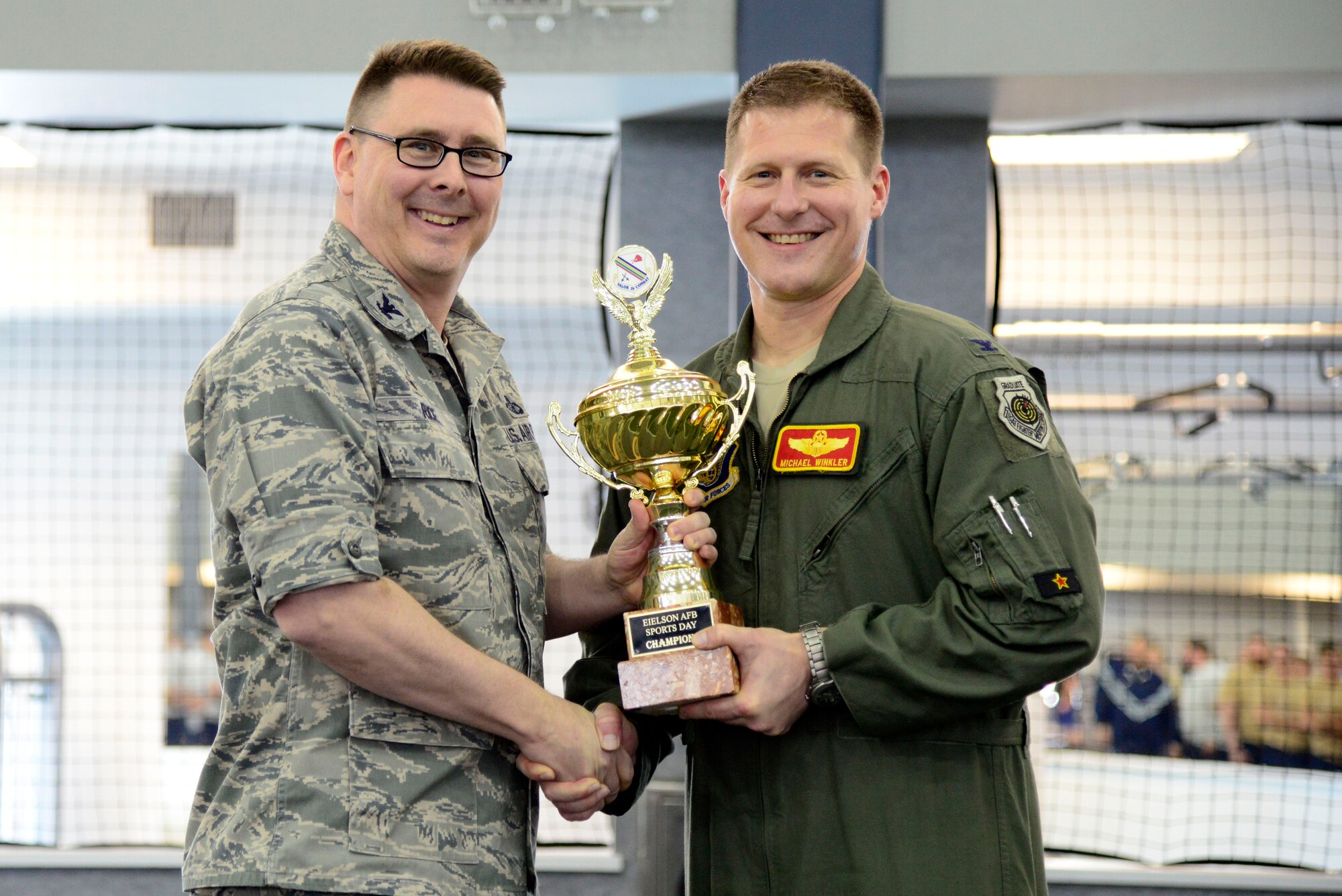 U.S. Air Force Col. Larry Rice, left, the 354th Mission Group commander, accepts the Fighter Wing (FW) Sports Day first place trophy from Col. Michael Winkler, right, the 354th FW commander, during the sports day ceremony at Eielson Air Force Base, Alaska, March 30, 2015. The 354th Force Support Squadron coordinated the all-day event to give Airmen the opportunity to engage in fitness and friendly competitions. (U.S. Air Force photo by Senior Airman Racheal E. Watson/Released)