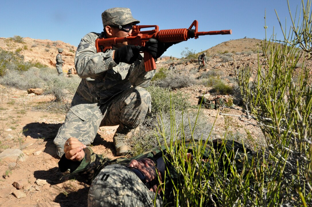 Senior Airman Chris Mendoza, a medical professional assigned to the 624th Aeromedical Staging Squadron, Joint Base Pearl Harbor-Hickam, Hawaii, establishes security before treating a simulated casualty during Operation Joint Medic at Nellis Air Force Base, Nev., March 27, 2015. The exercise scenario had the participants treating and evacuating 27 simulated casualties while under fire. (U.S. Air Force photo by Tech. Sgt. Colleen Urban)