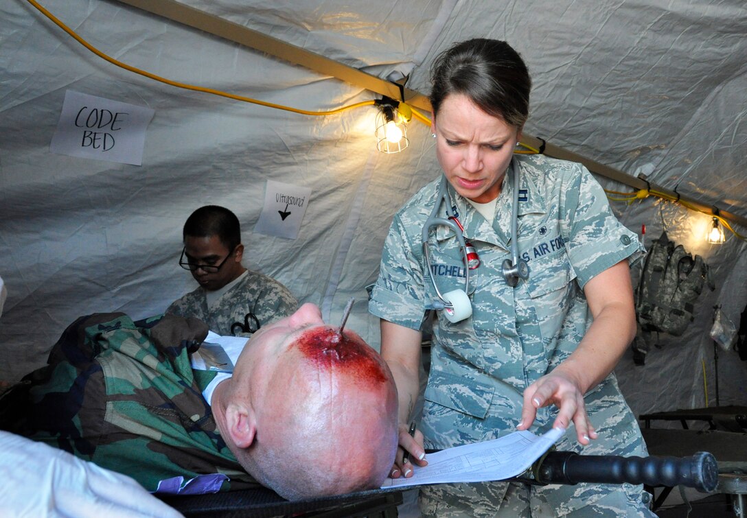 Capt. Diana Mitchell, a medical officer assigned to the 926th Aerospace Medicine Squadron, assesses simulated injuries on Master Sgt. Frank Preuss during Operation Joint Medic at Camp Cobra on Nellis Air Force Base, Nev., March 27, 2015. The exercise helped medical personnel handle stressful situations with minimal resources. (U.S. Air Force photo by Tech. Sgt. Colleen Urban)