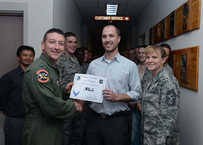 William Hall, center, 47th Civil Engineer Squadron civil engineer, poses with Col. Brian Hastings, 47th Flying Training Wing commander and Chief Master Sgt. Teresa Clapper, 47th FTW command chief, after accepting the XLer of the week award here March 25, 2015. The XLer is a weekly award chosen by wing leadership and was presented to Hall for his work in maintaining Laughlin’s runway with minimal impact to the wing mission. (U.S. Air Force photo by Airman 1st Class Jimmie D. Pike)(Released)
