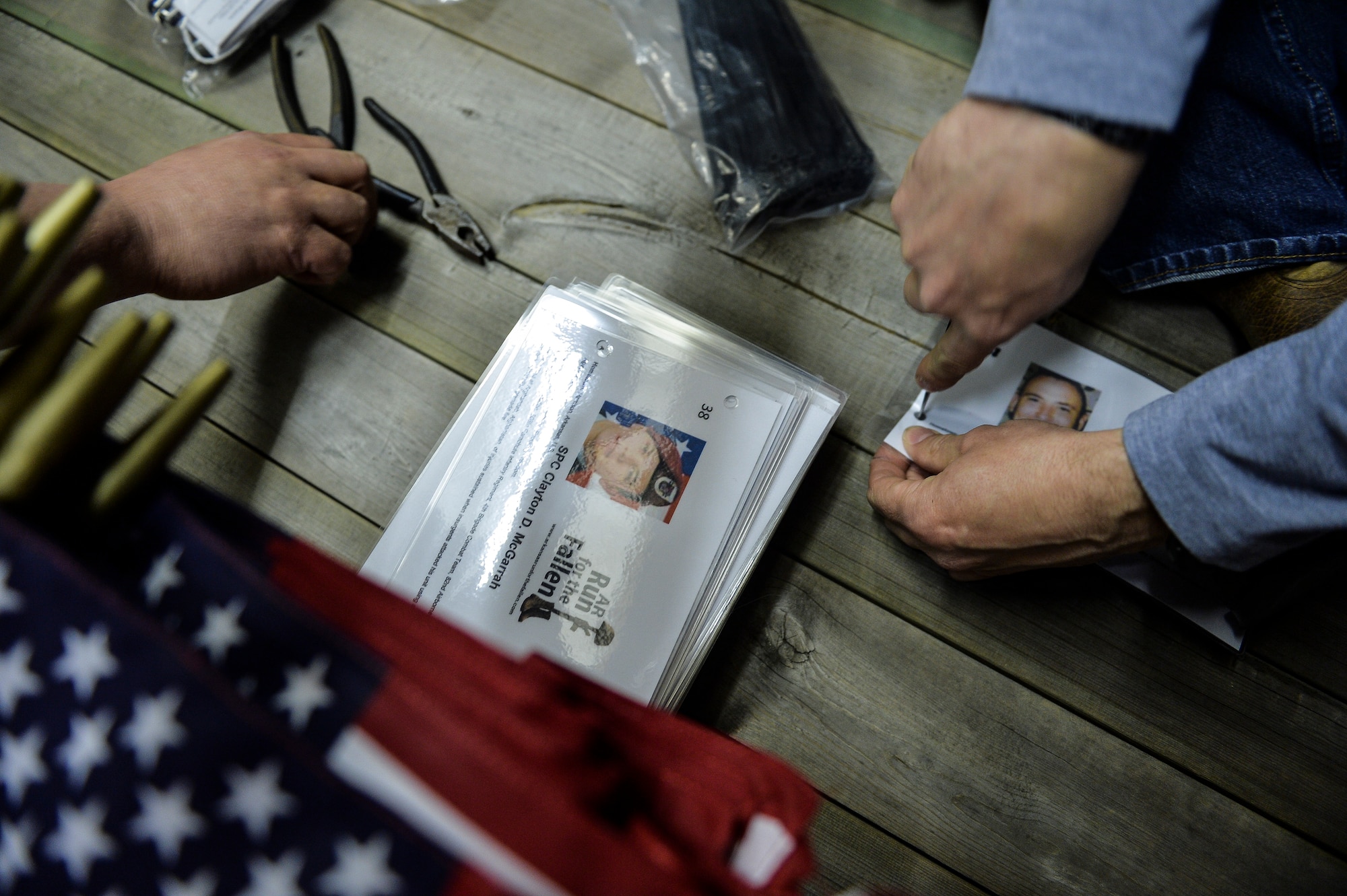 Volunteers tie the biographies of fallen Arkansan service members to American flags to be placed at every mile marker March 22, 2015, in Ozark, Ark. Participants placed 146 flags along Arkansas Highway 64, from Ozark, to Little Rock, Ark. (U.S. Air Force photo/Senior Airman Cliffton Dolezal)) 
