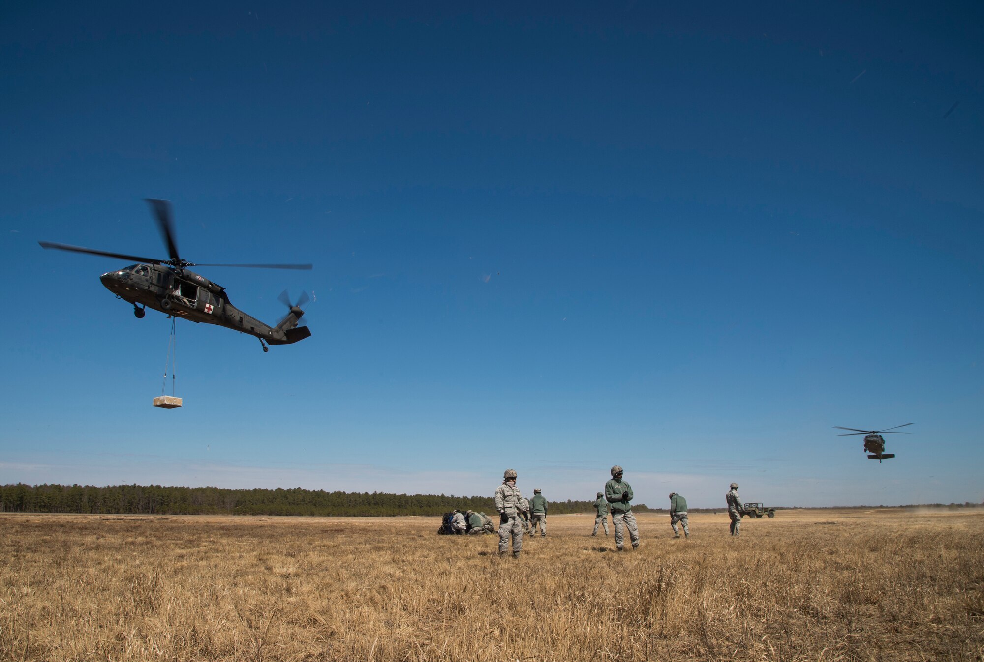 A U.S. Army UH-60 Black Hawk helicopter assigned to the 1-150th Assault Helicopter Battalion lifts cargo as another Black Hawk waits for its turn to be hooked up with cargo by Airmen assigned to the 621st Contingency Response Wing during sling-load training at Joint Base McGuire-Dix-Lakehurst, N.J., April 1, 2015. Sling-load operations are useful particularly in areas where aircraft are too big to land or airfields are not safe for oversized aircraft to operate. They also offer a quicker delivery time for cargo such as food and supplies in an uncertain environment. (U.S. Air Force photo/Staff Sgt. Gustavo Gonzalez/RELEASED)