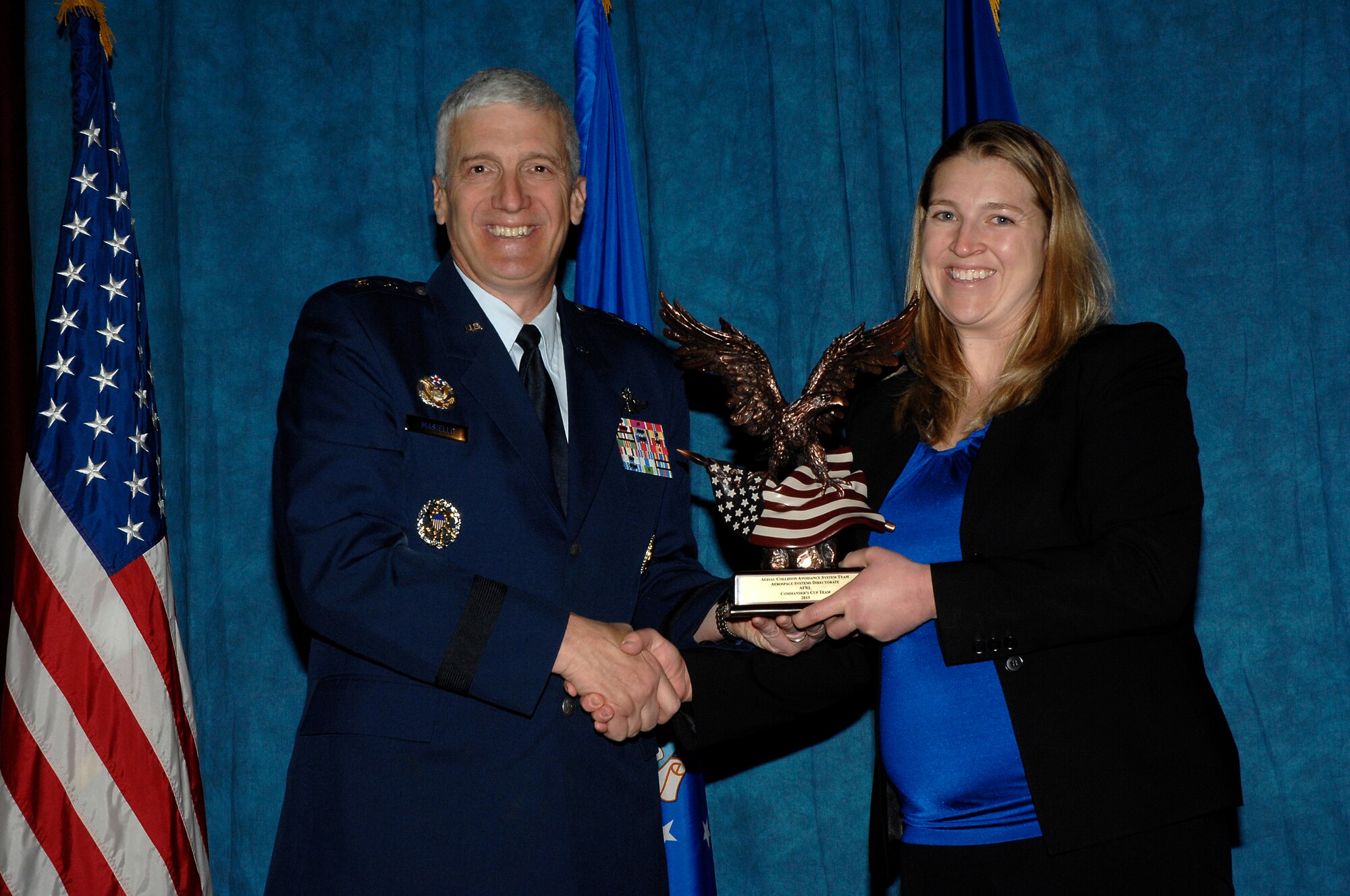 Maj. Gen. Tom Masiello, AFRL commander, presents Amy Burns, a member of the Aerial Collision Avoidance System Team, with a Commander’s Cup Team award during the 2015 AFRL Annual Awards ceremony. (U.S. Air Force photo by Albert Bright)